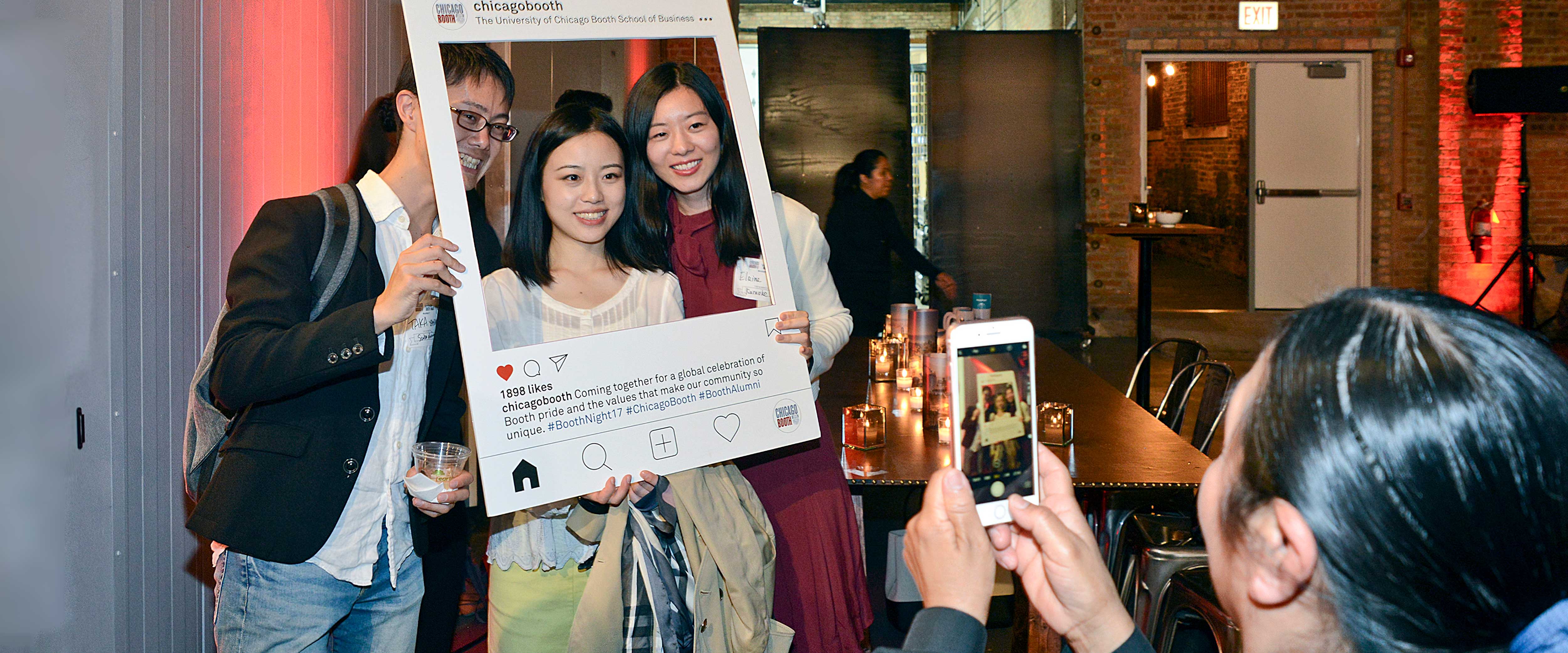 Man and two women pose in an Instagram oversized frame