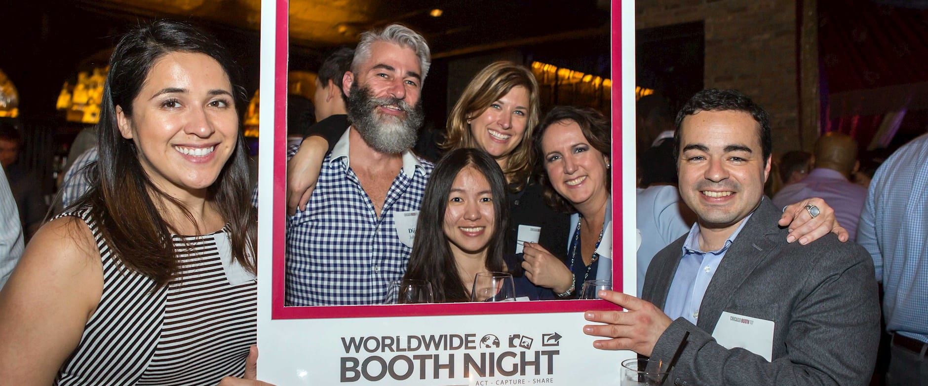 People posing with a social media frame at a Worldwide Booth Night event