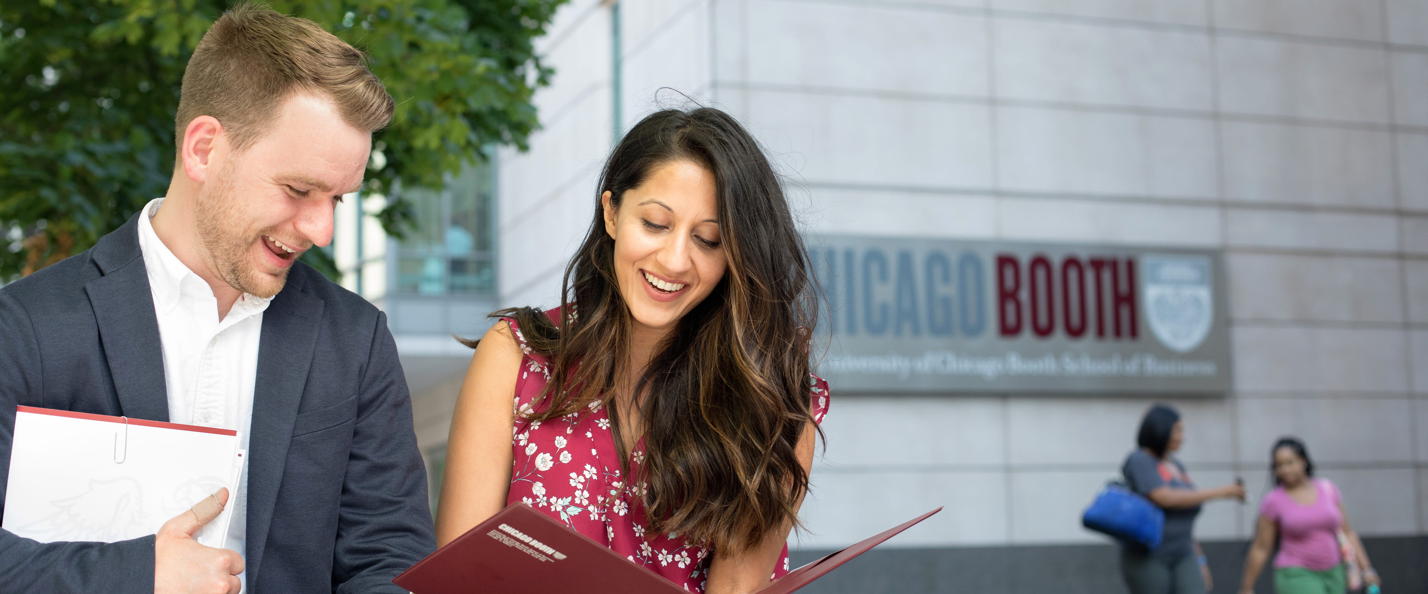 Two students in front of Gleacher Center's Booth sign. 