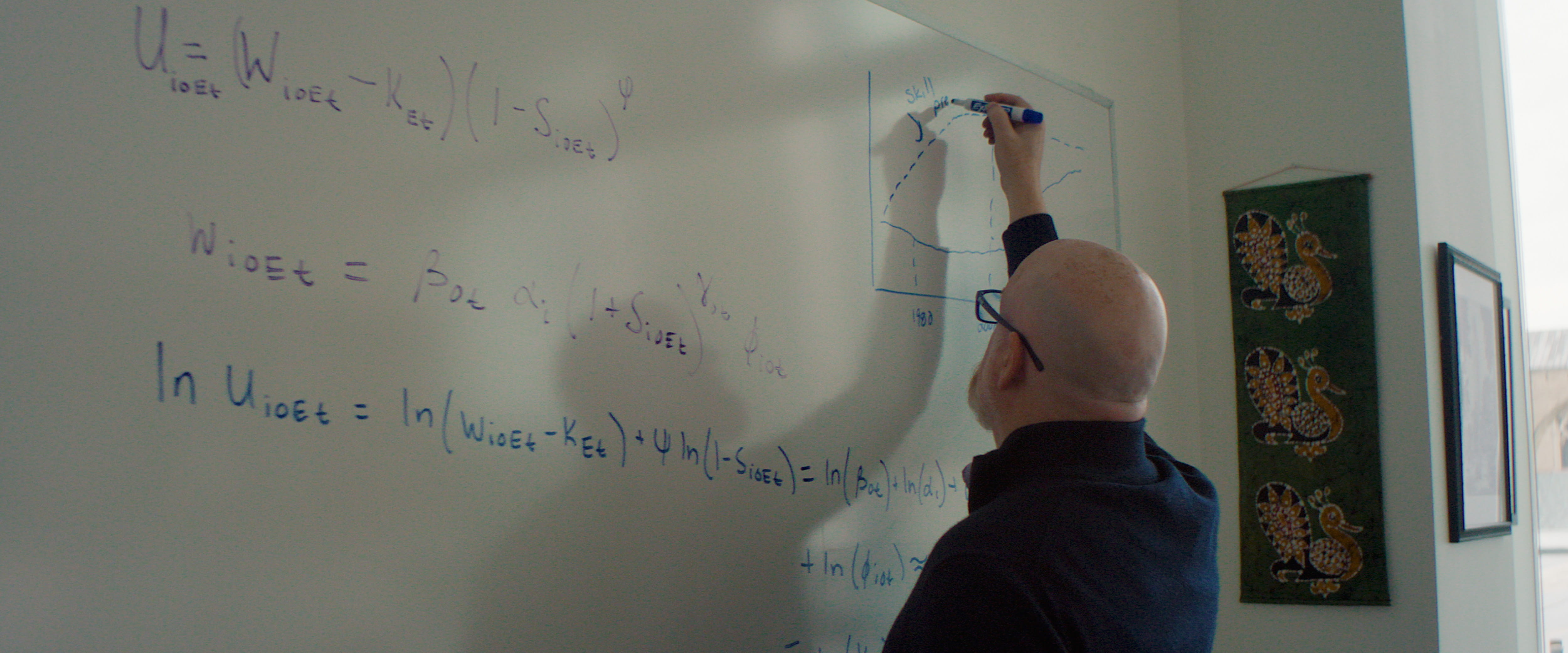 Erik Hurst writes with blue marker on a whiteboard