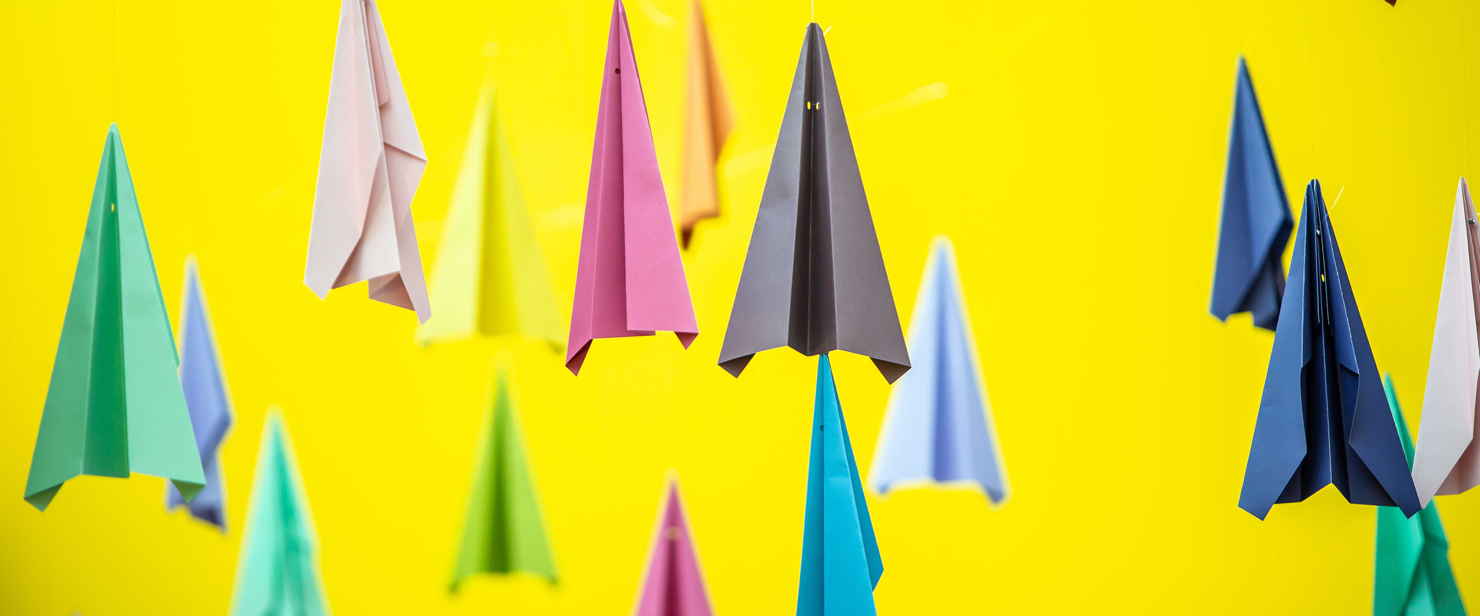 Colorful paper airplans pointed at the ceiling