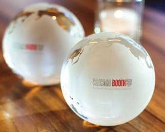 Two Chicago Booth clear globe paperweights on a table  