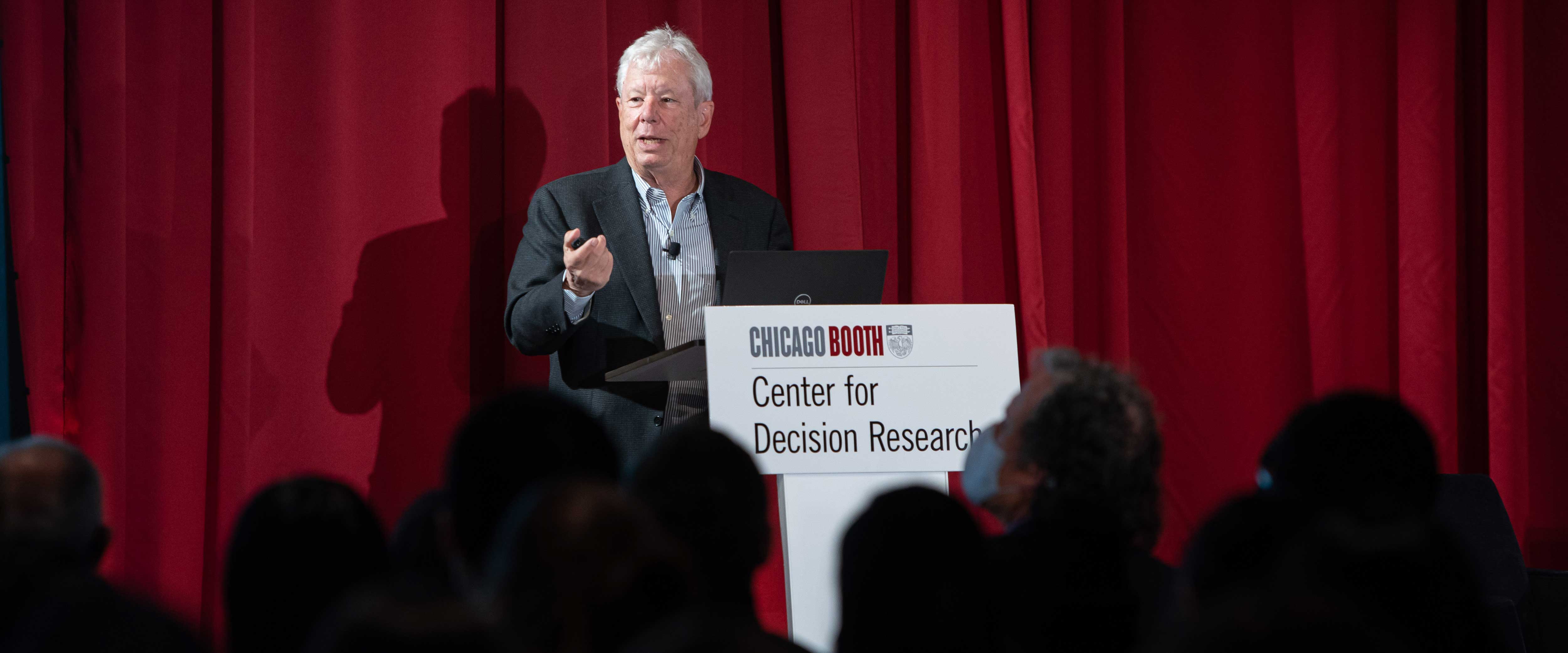 Richard Thaler speaking from a podium at a Center for Decision Research event