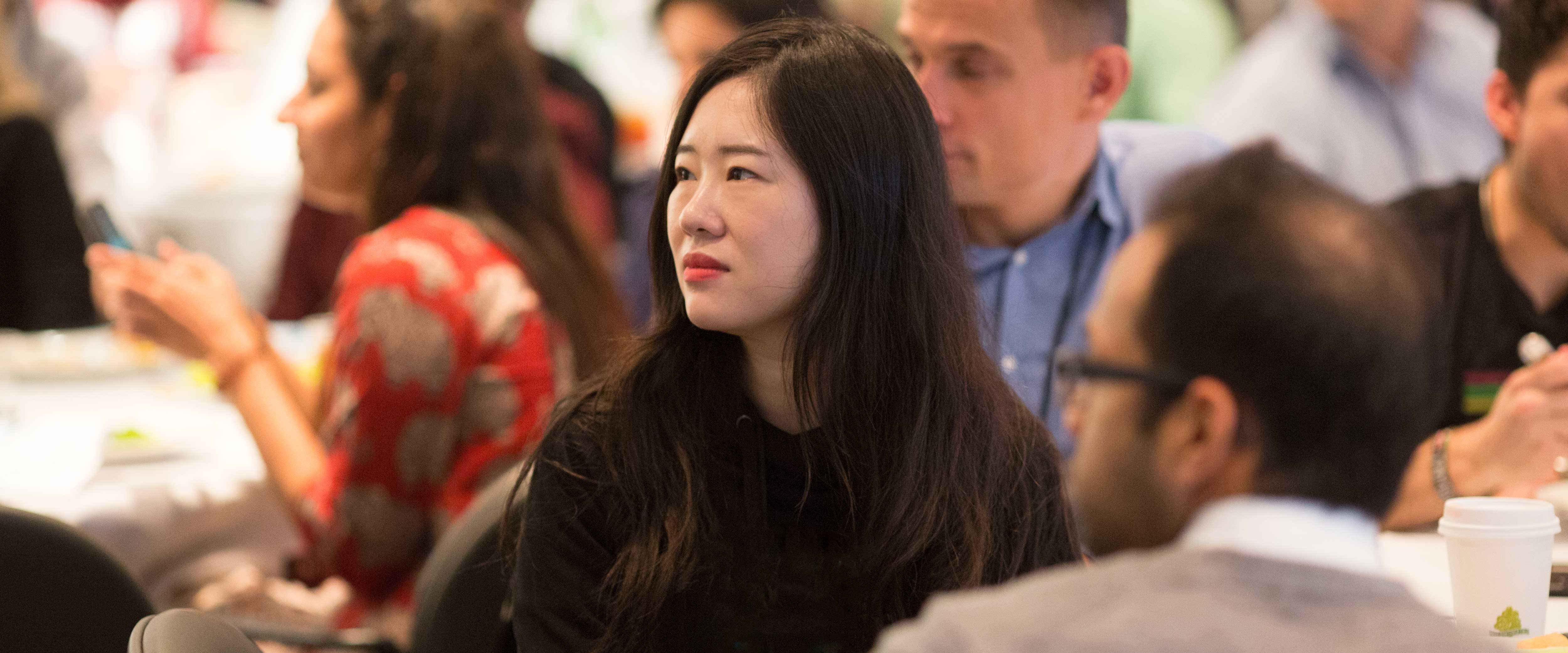 Woman at a luncheon table listening to a speaker