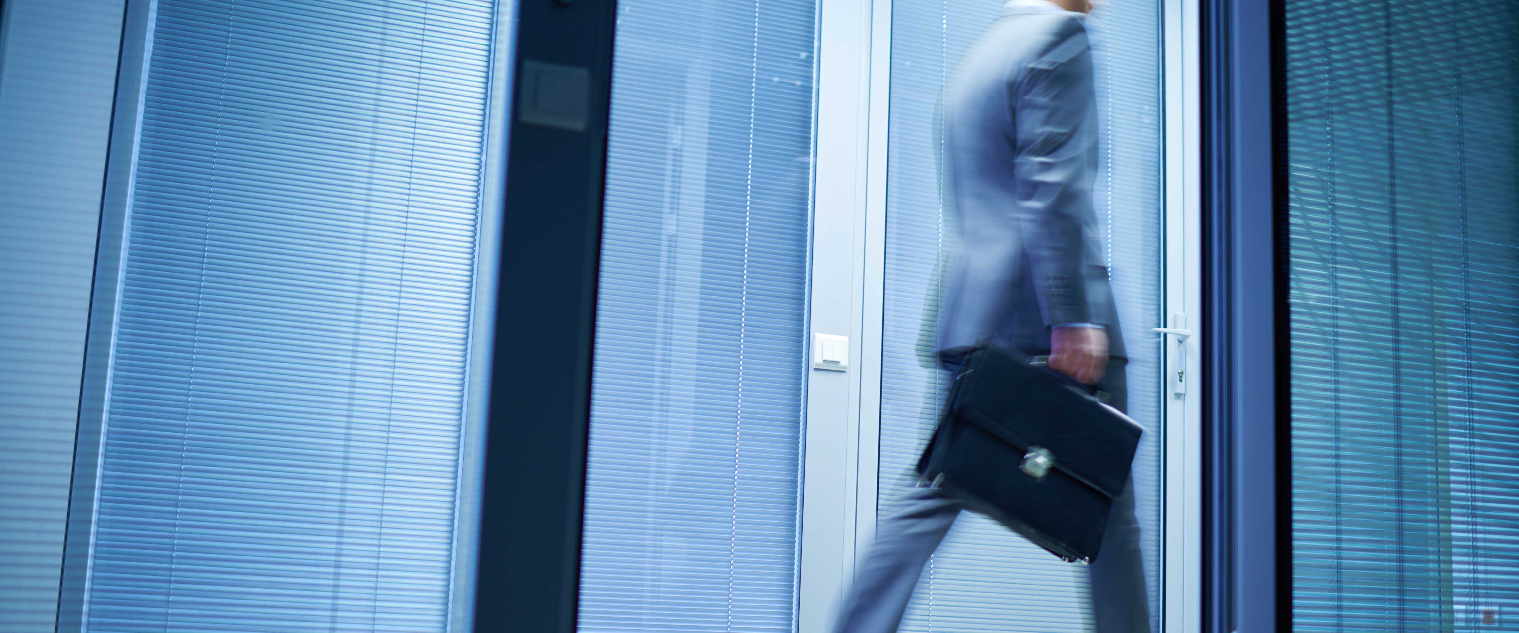 Side view of businessman walking past office carrying a briefcase