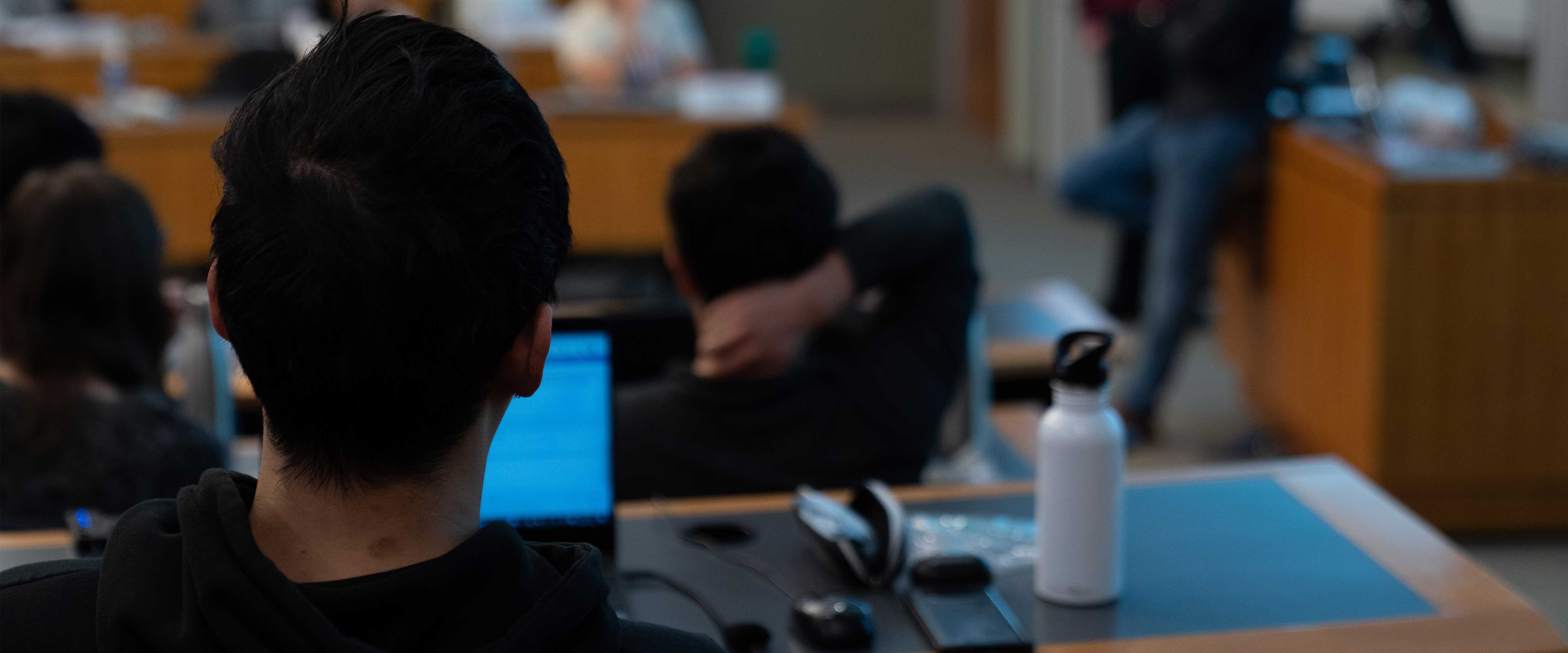 Chicago Booth student sitting in a Harper Center classroom with laptop