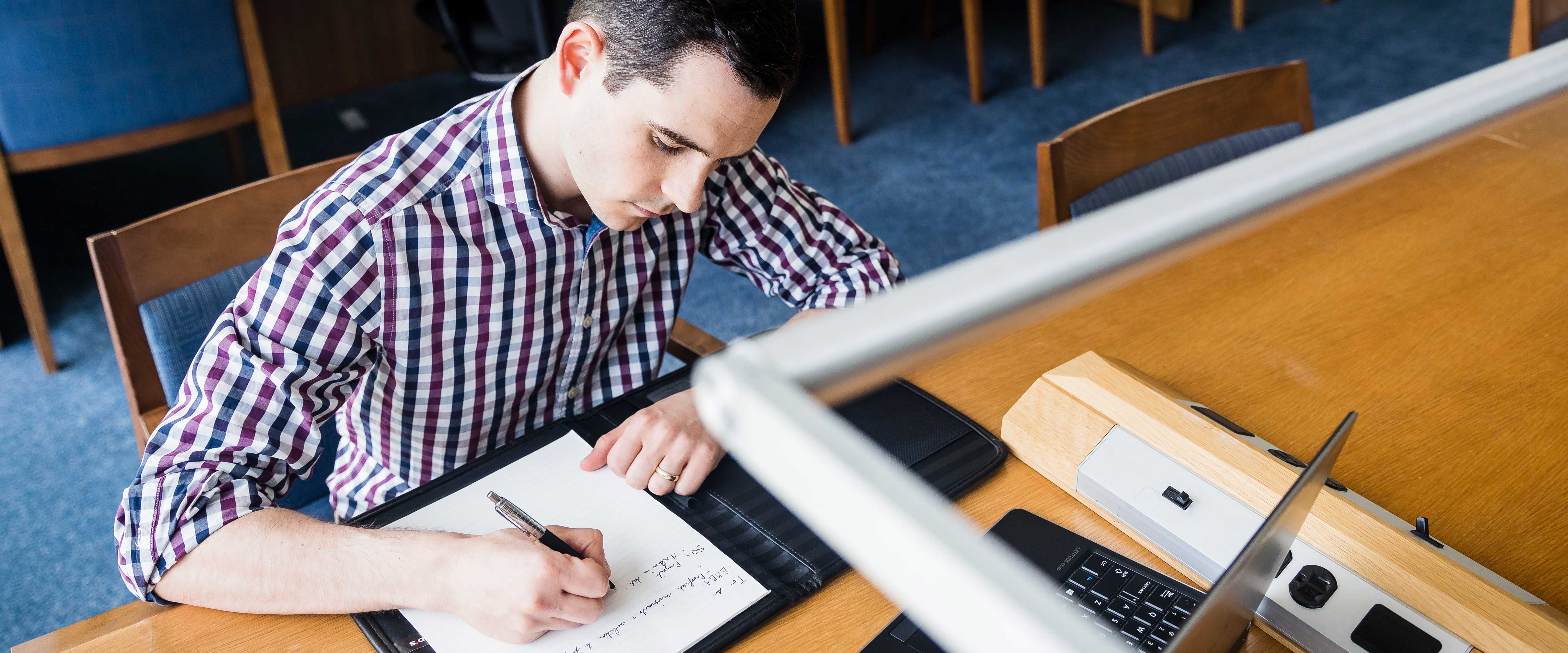 Man writing in a notebook studying 