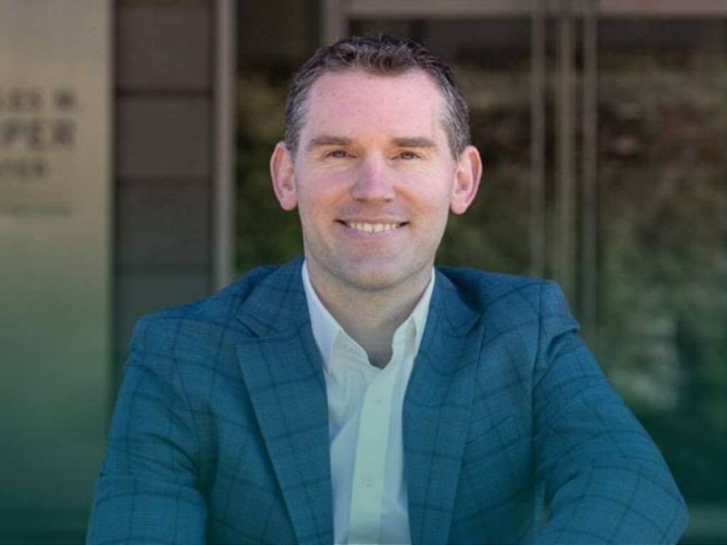 Man in a blue suit jacket and button down shirt.
