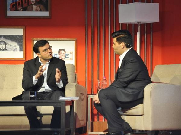 Two men converse on stage while seated