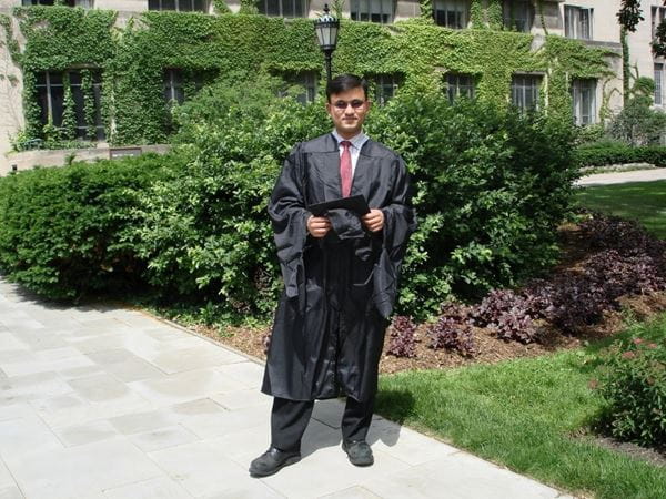 Man in graduation robe holds diploma