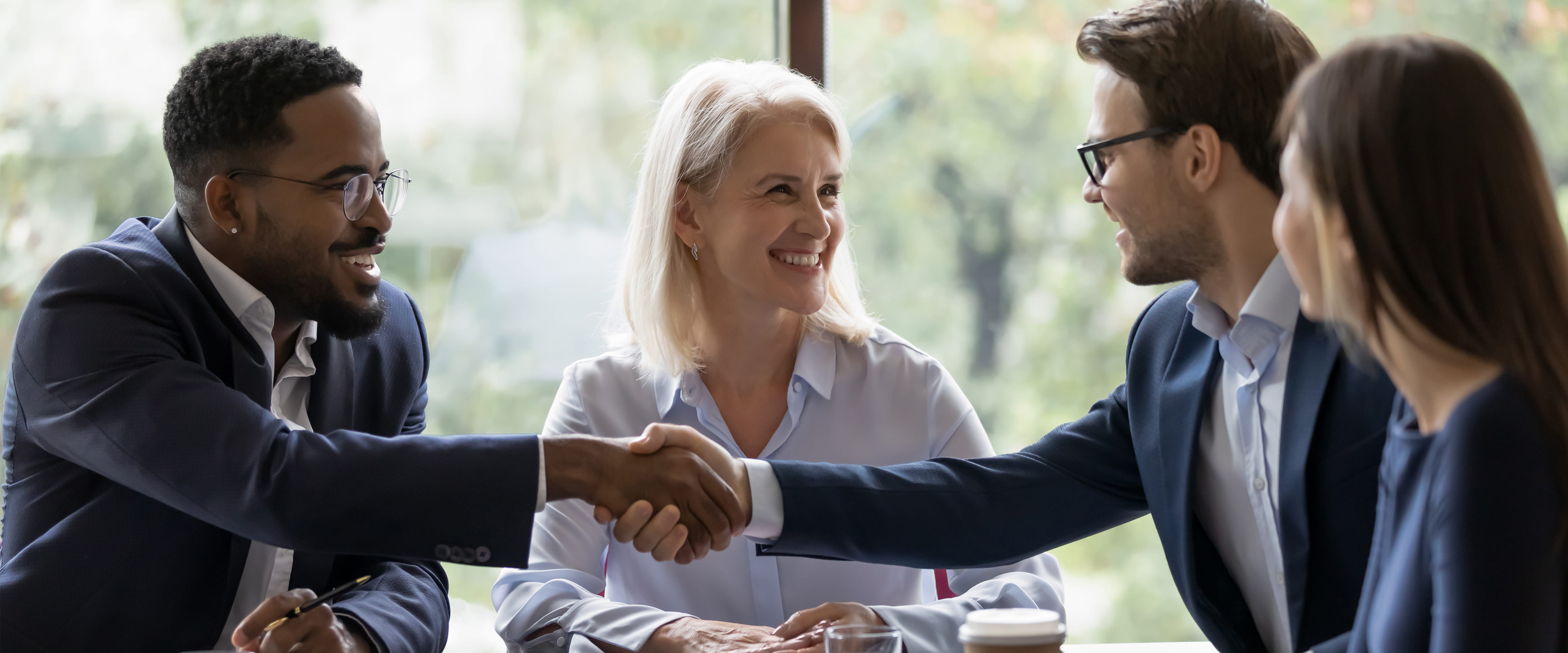 Four business people shaking hands and smiling