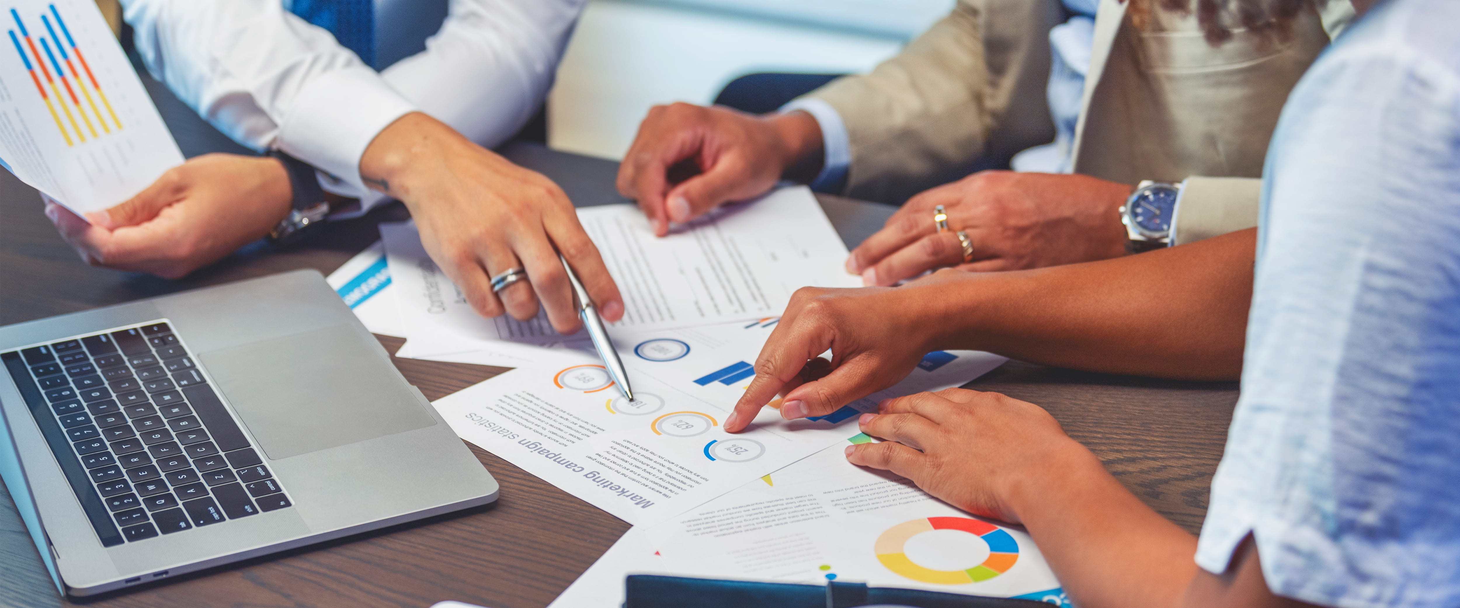 People pointing at printed out business documents on a table