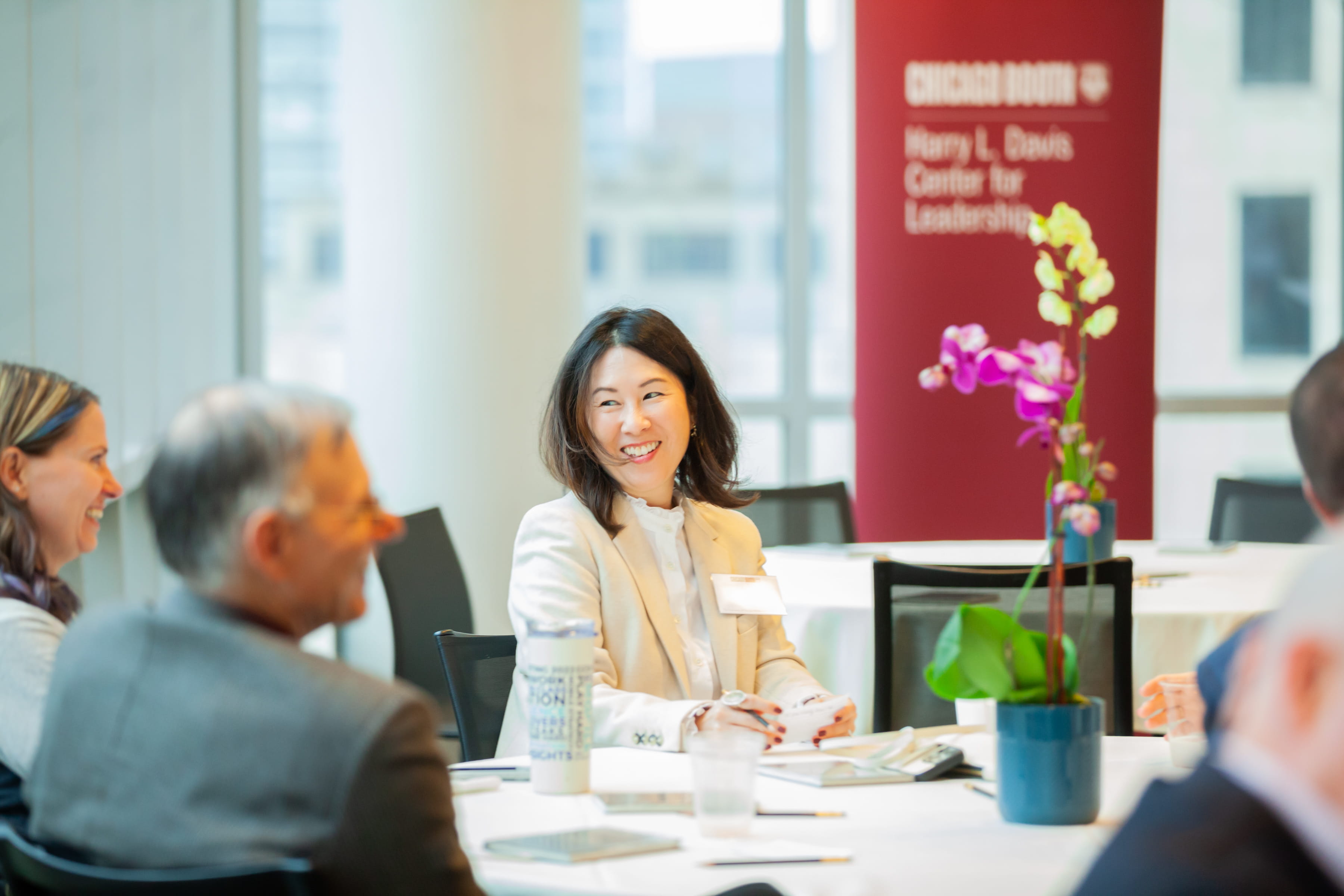 Woman sitting at round table smiles at table mates in foreground