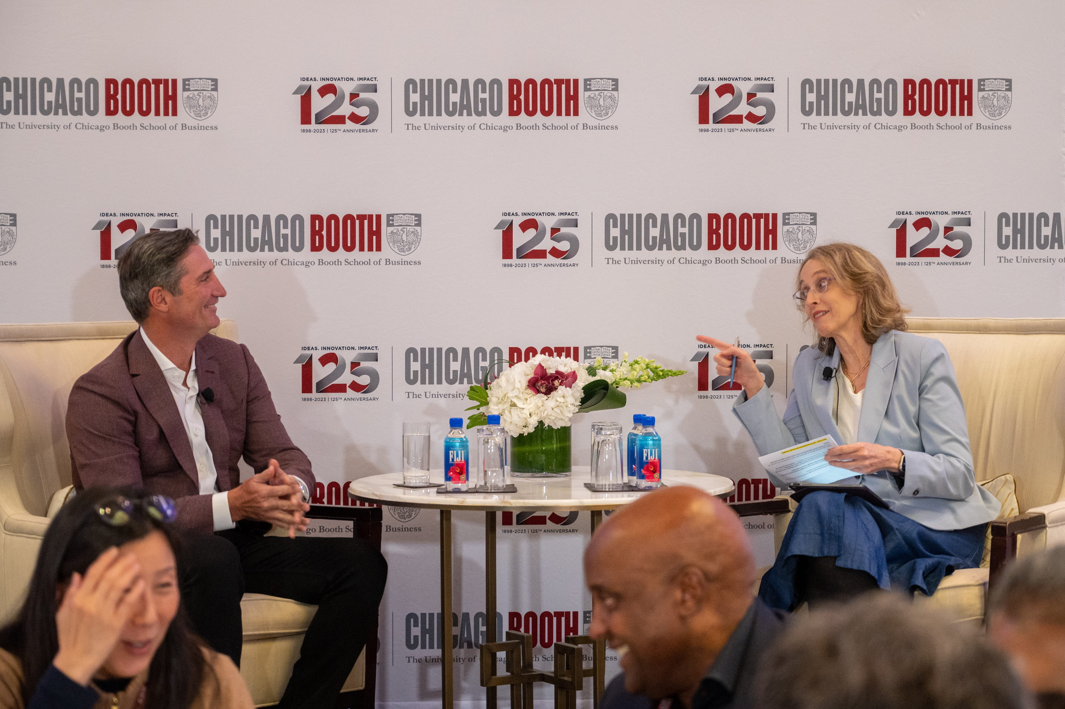 man and woman sitting down in armchairs on a stage in conversation