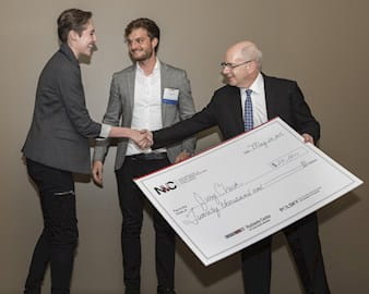 Founders of JuryCheck with their giant check in 2017 shaking hands