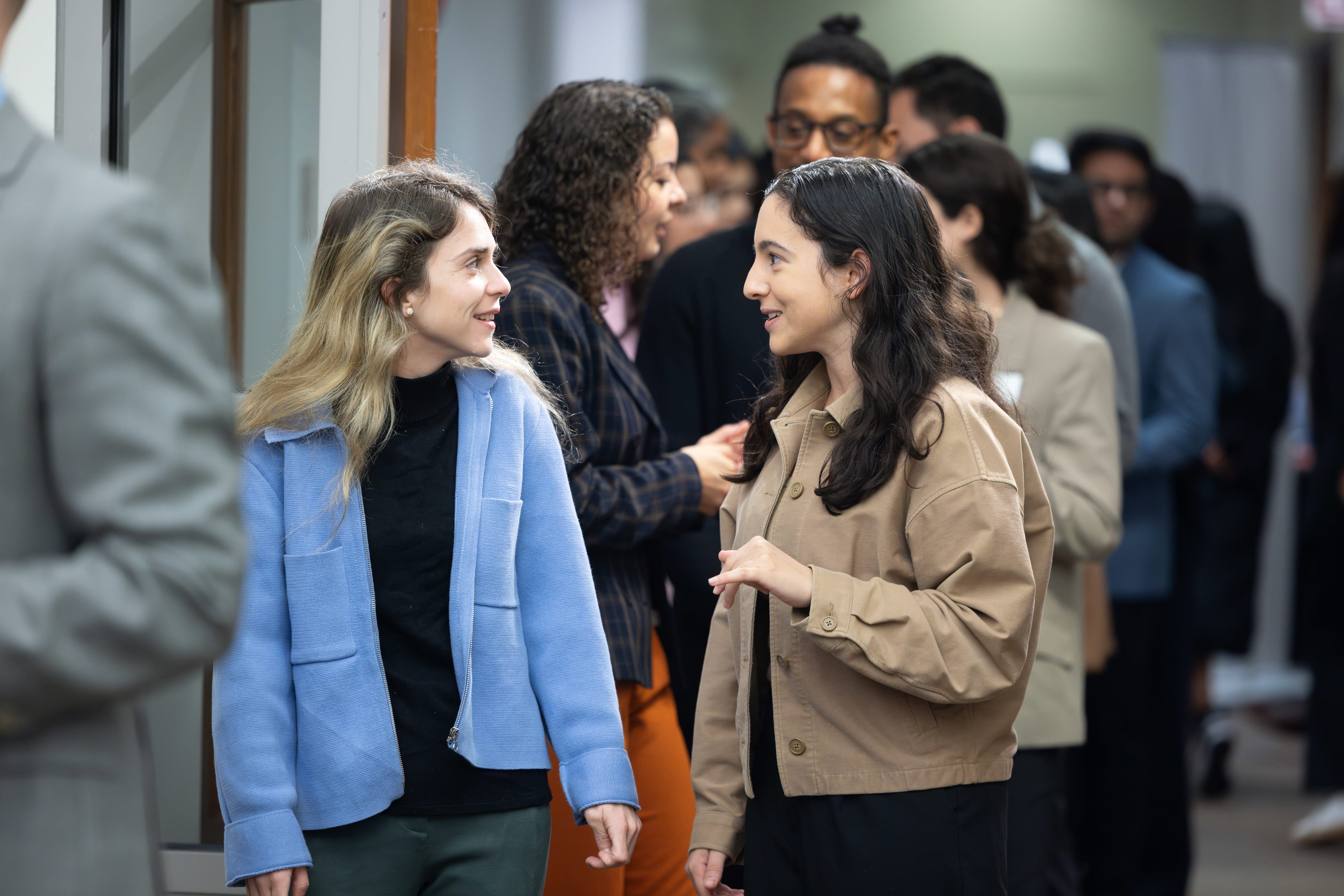Two women talking to each other with several other people behind them
