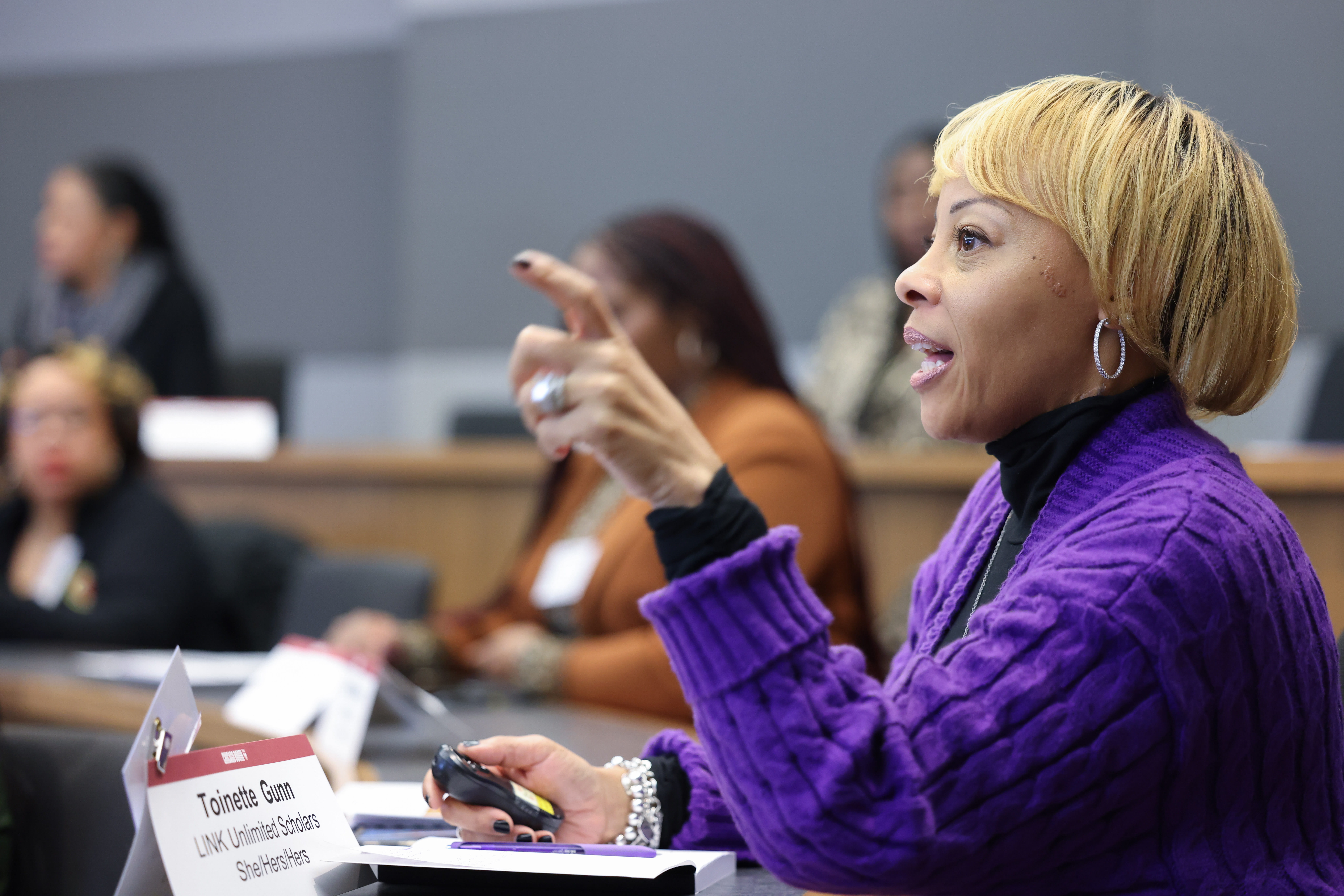 Woman wearing purple sweater talking in a classroom