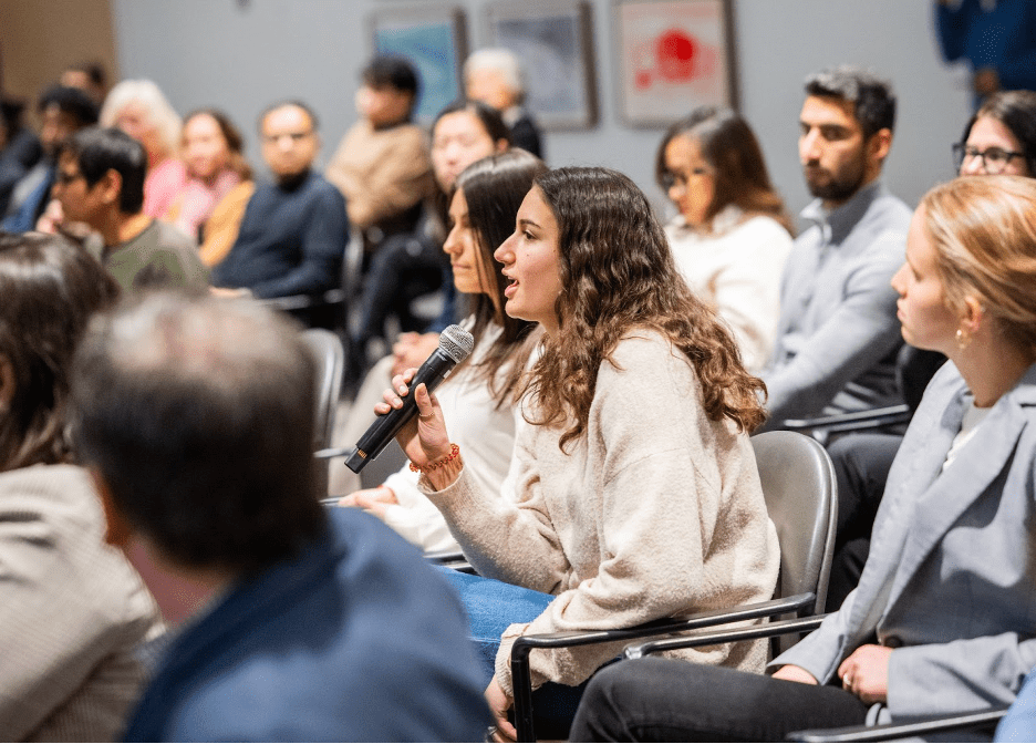 A woman speaks into a microphone in a classroom setting