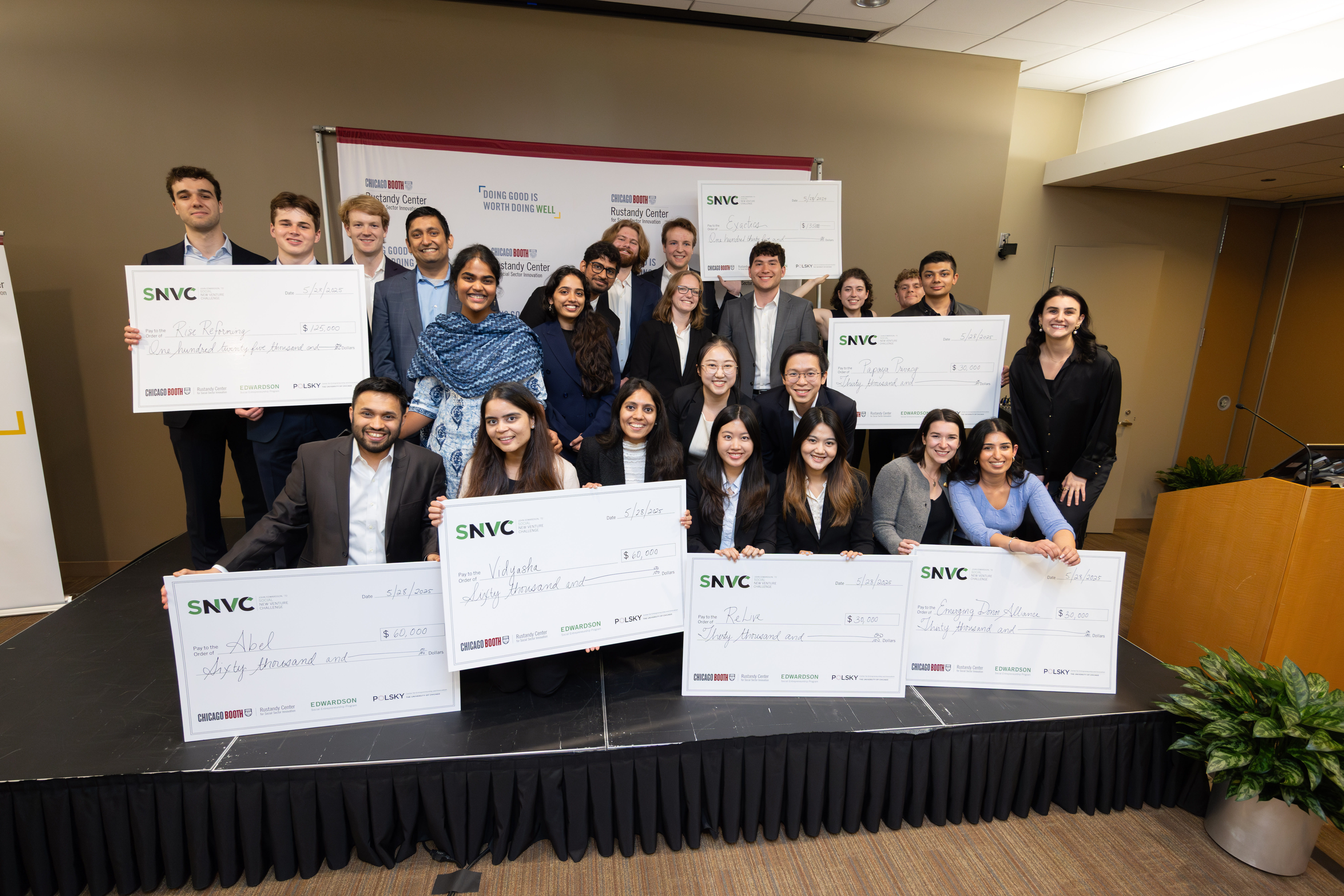 A group of people smiling at the camera while holding up oversized checks