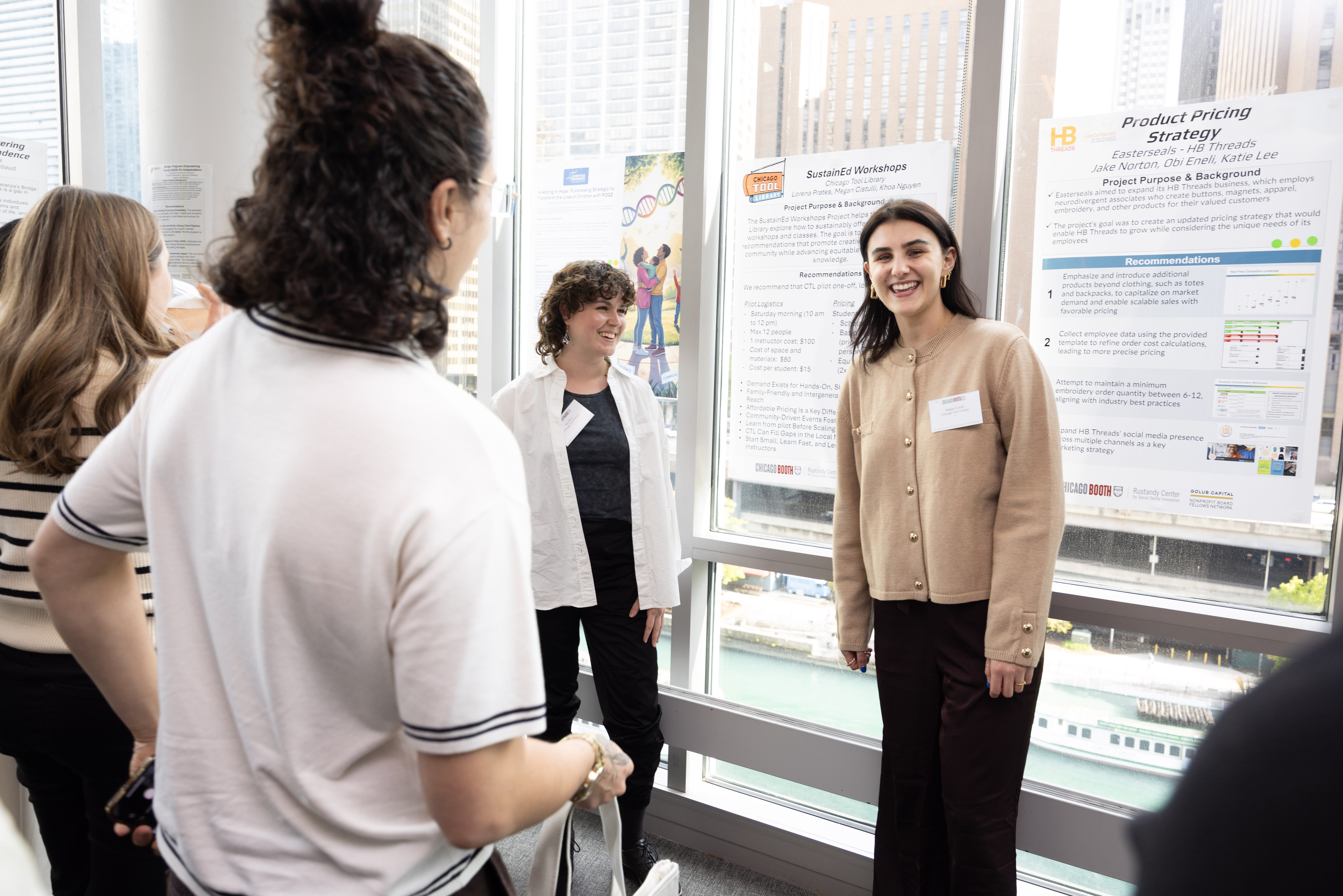 A woman stands in front of a poster, talking to several other people