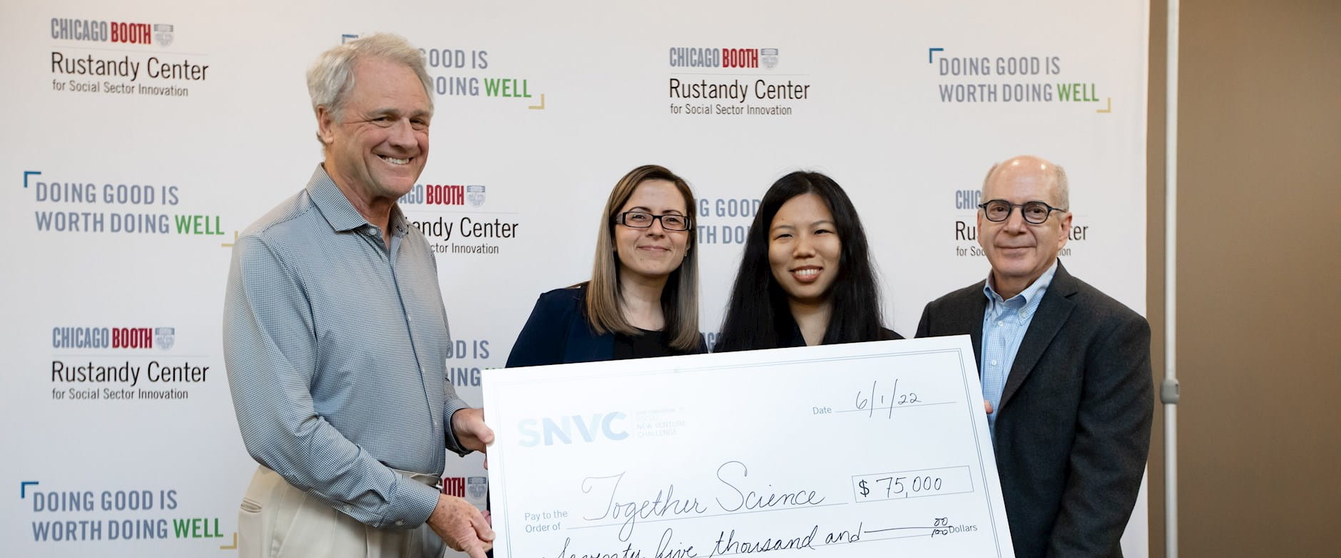 Four people holding an oversize check