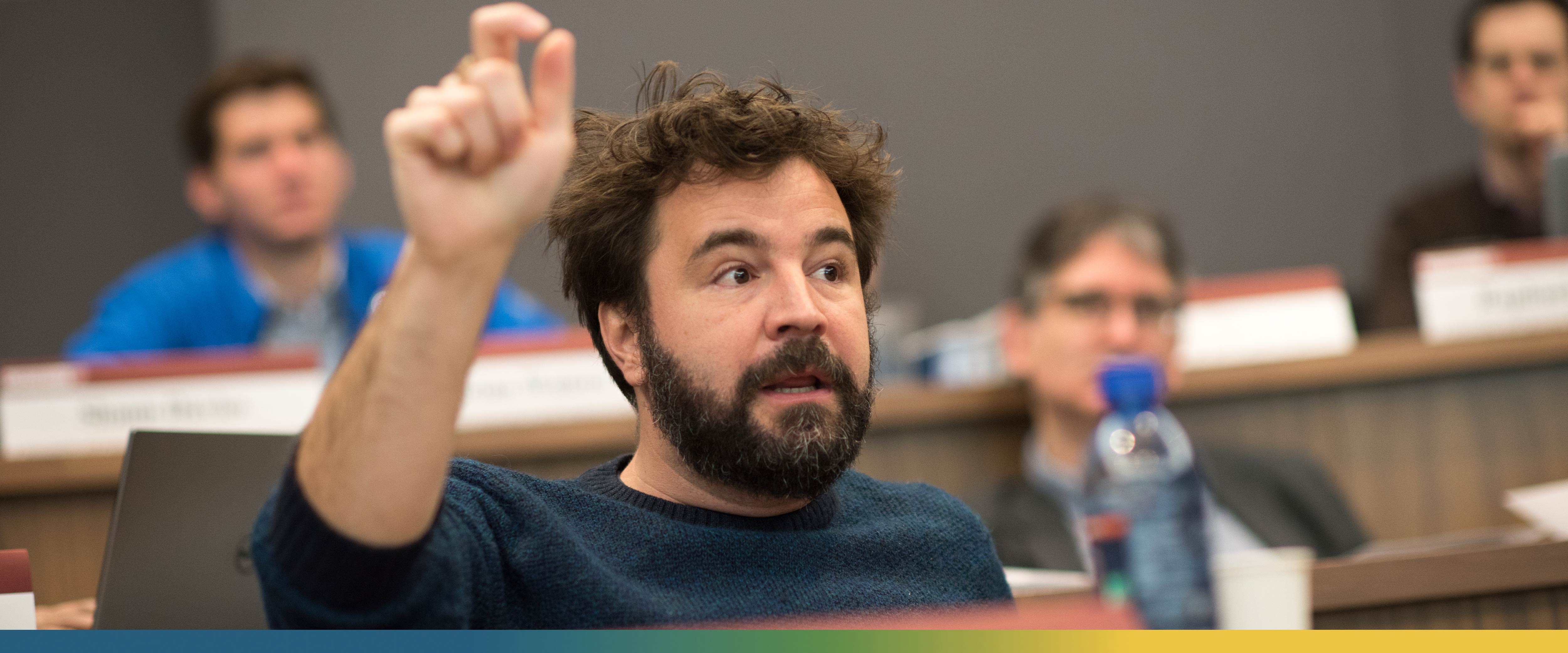 Emir Kamenica, Richard O. Ryan Professor of Economics and Neubauer Family Faculty Fellow, raising his hand to make a point