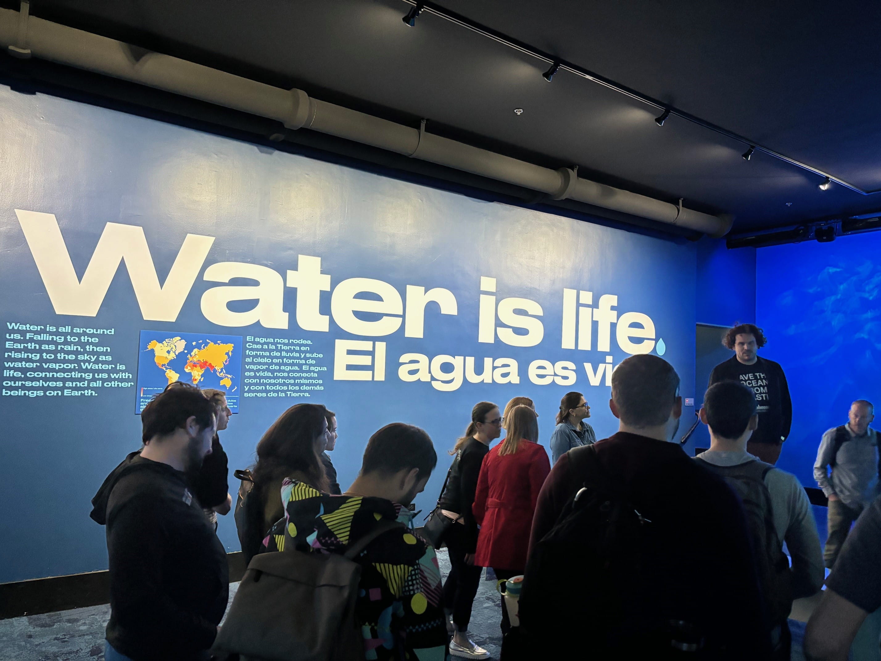 A group of people standing in front of a sign that says Water is life