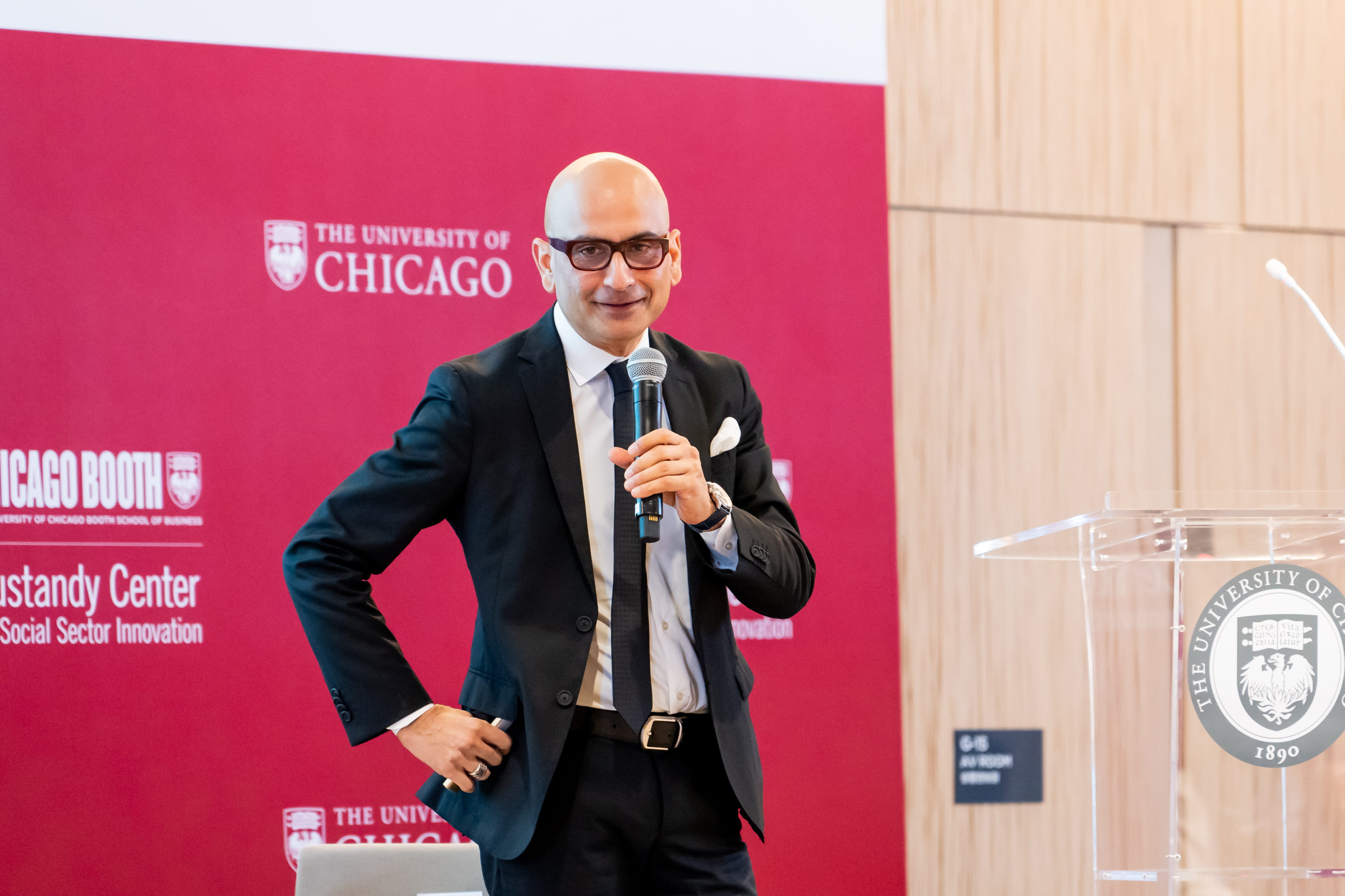 A man, Haresh Sapra, speaking through a microphone at an event