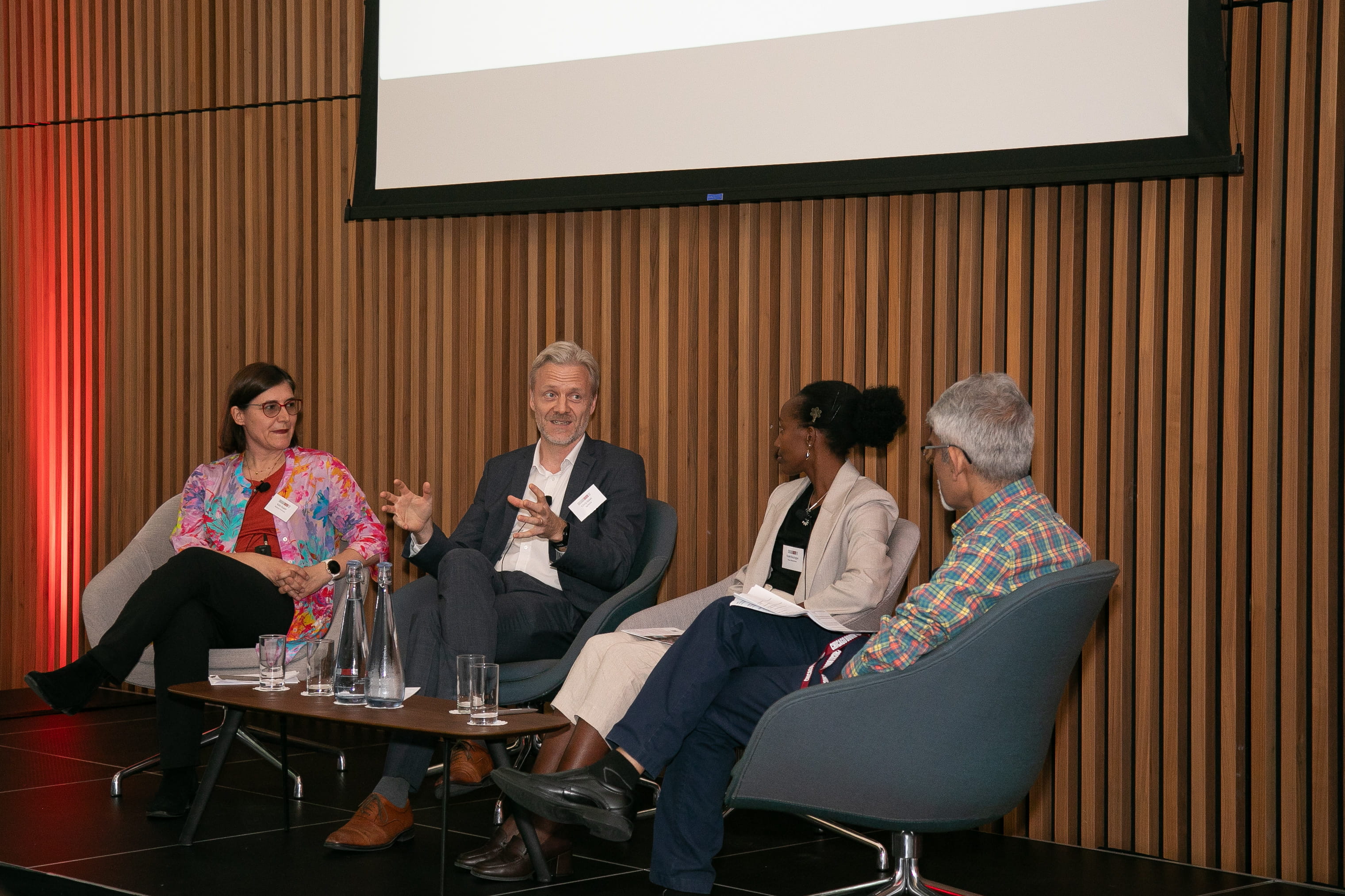 Four people sitting in chairs and talking 