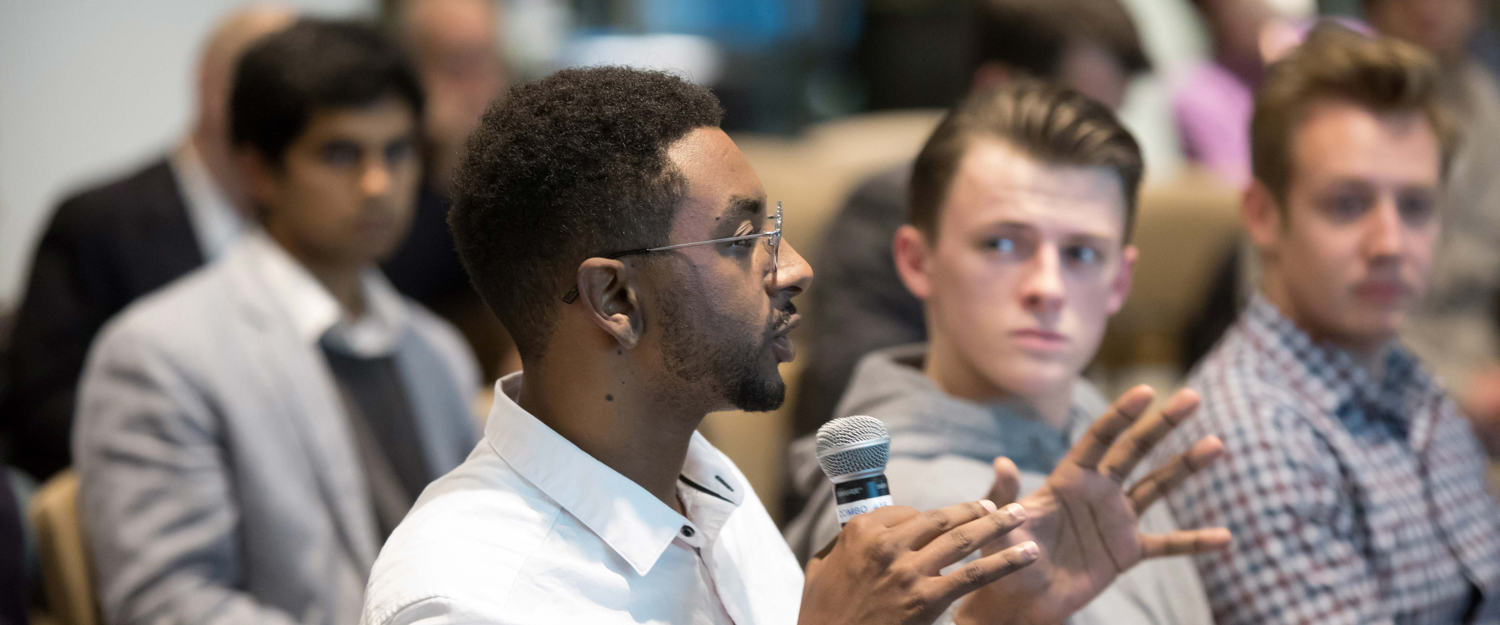 Man speaking in a group discussion holding a microphone
