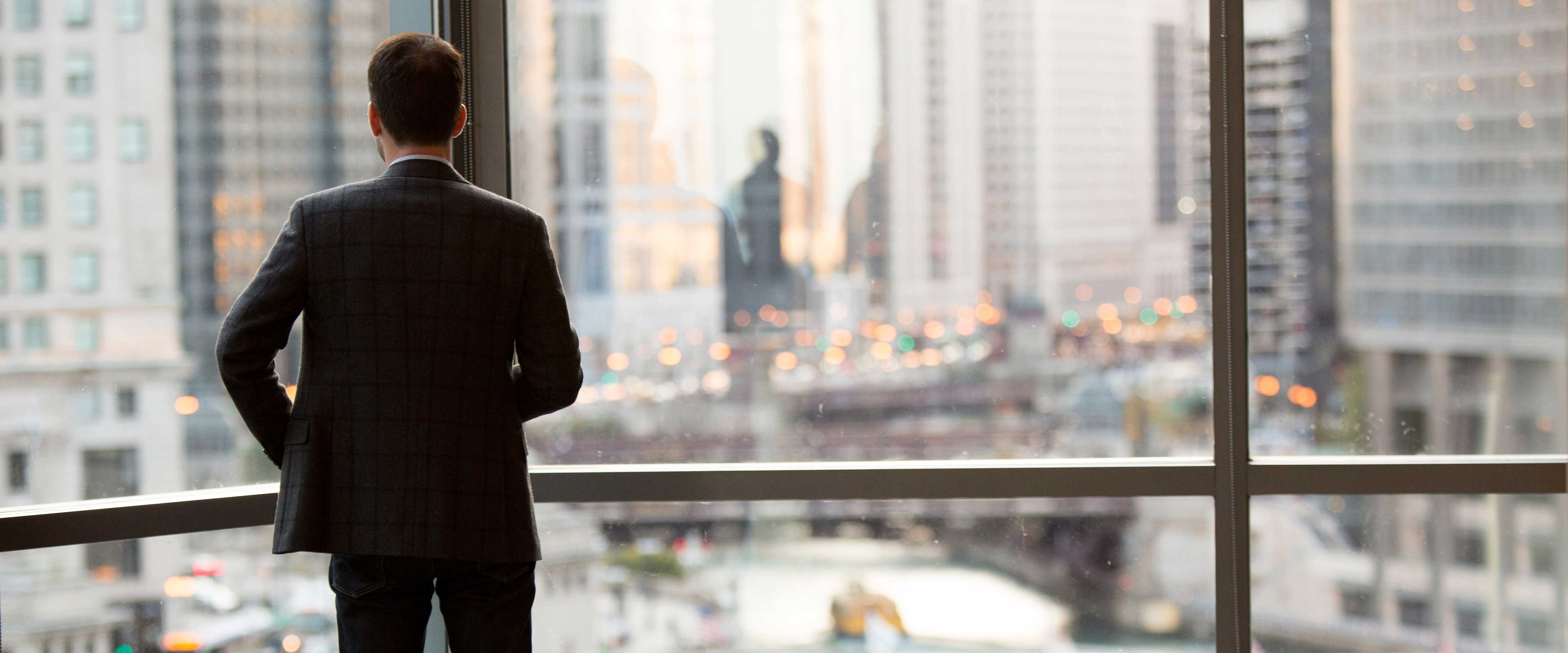 A businessman looking out the window in an urban environment
