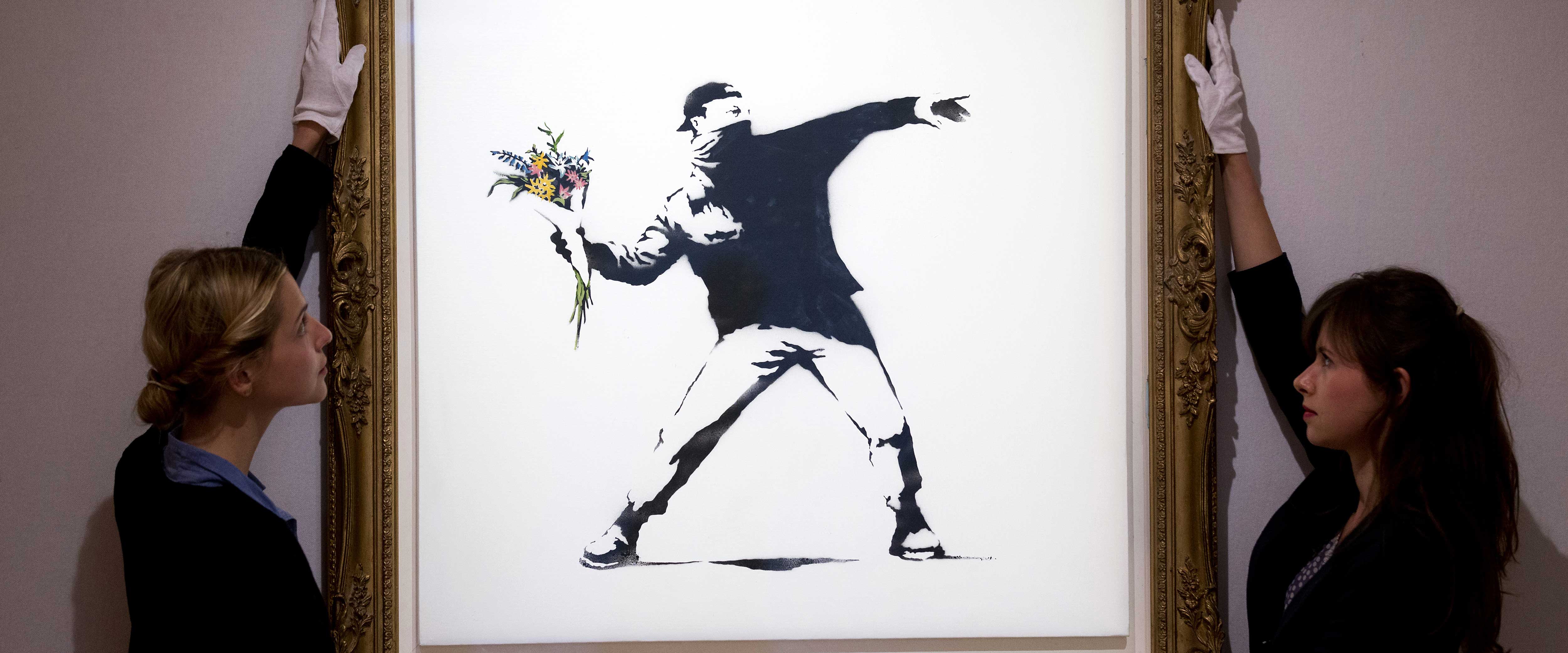 Gallery assistants holding a Banksy painting