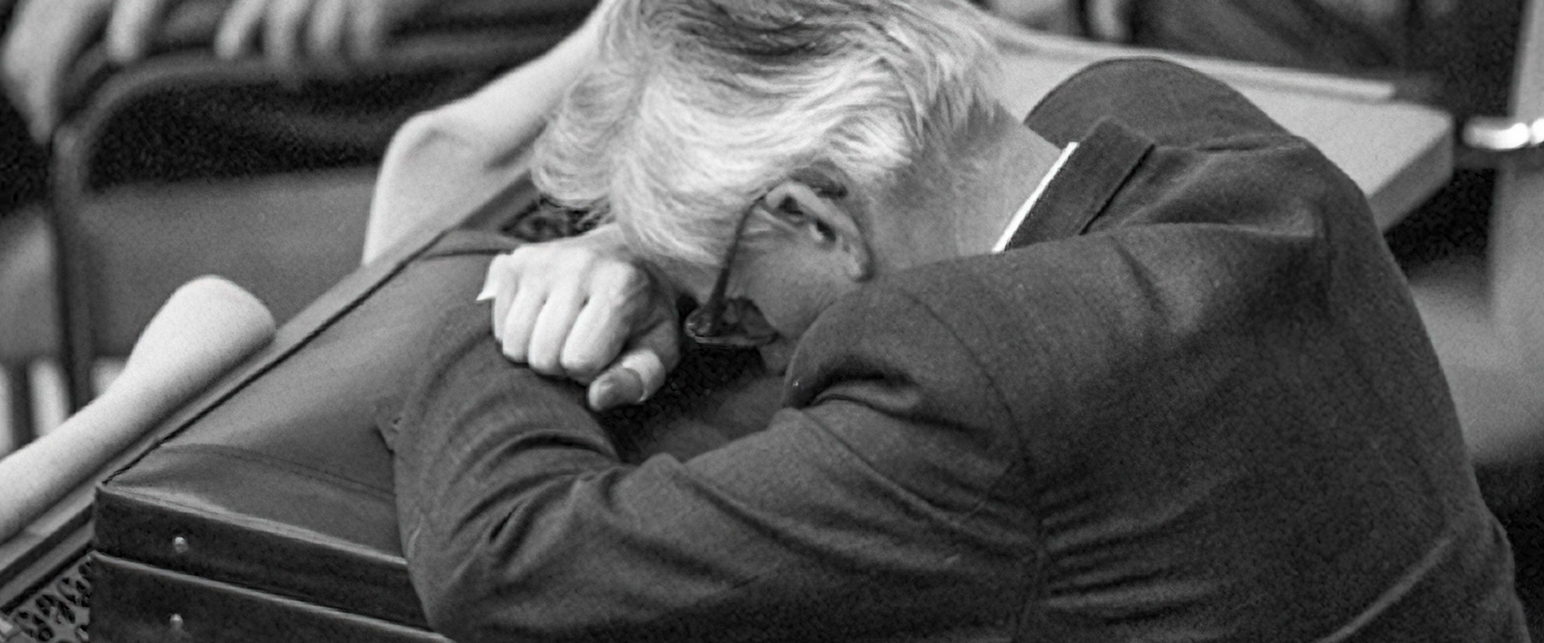Visibly stressed businessman resting on briefcase