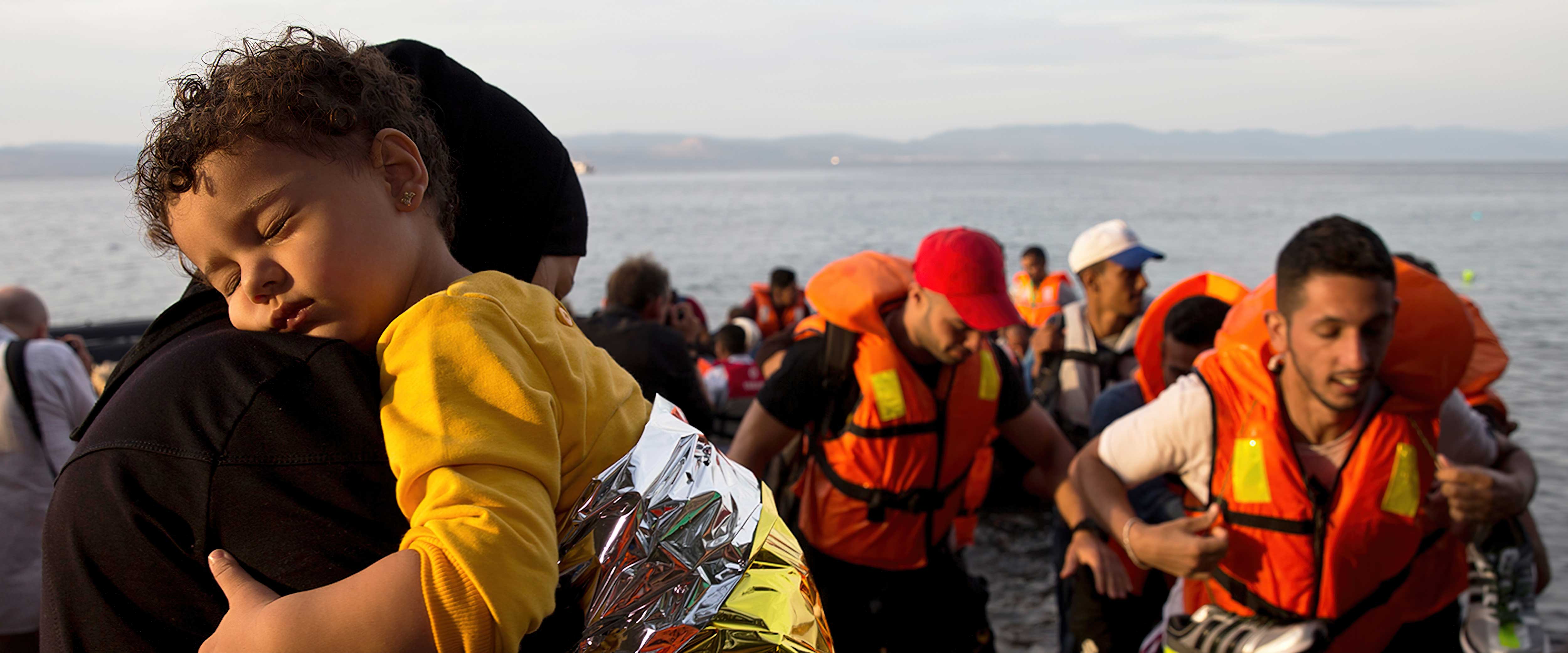 Refugee child asleep on adult's shoulder