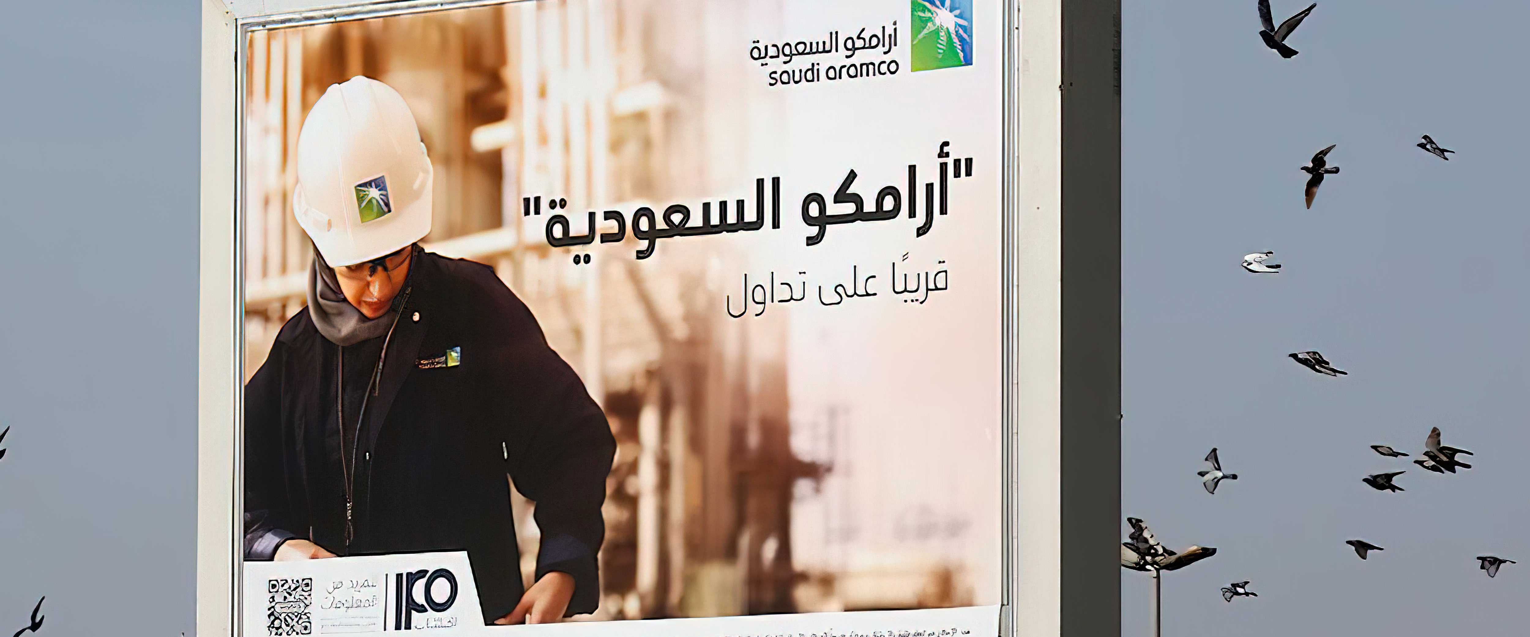 Billboard with person in a construction hat with birds flying around behind it