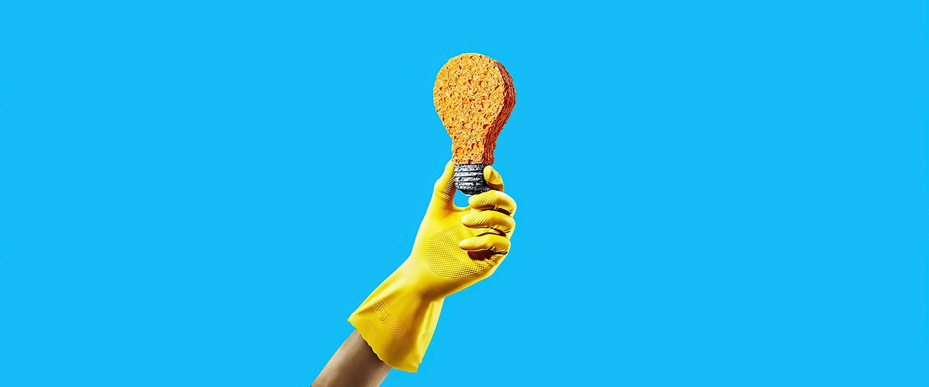 Hand in a dish washing glove holding up a lightbulb shaped sponge