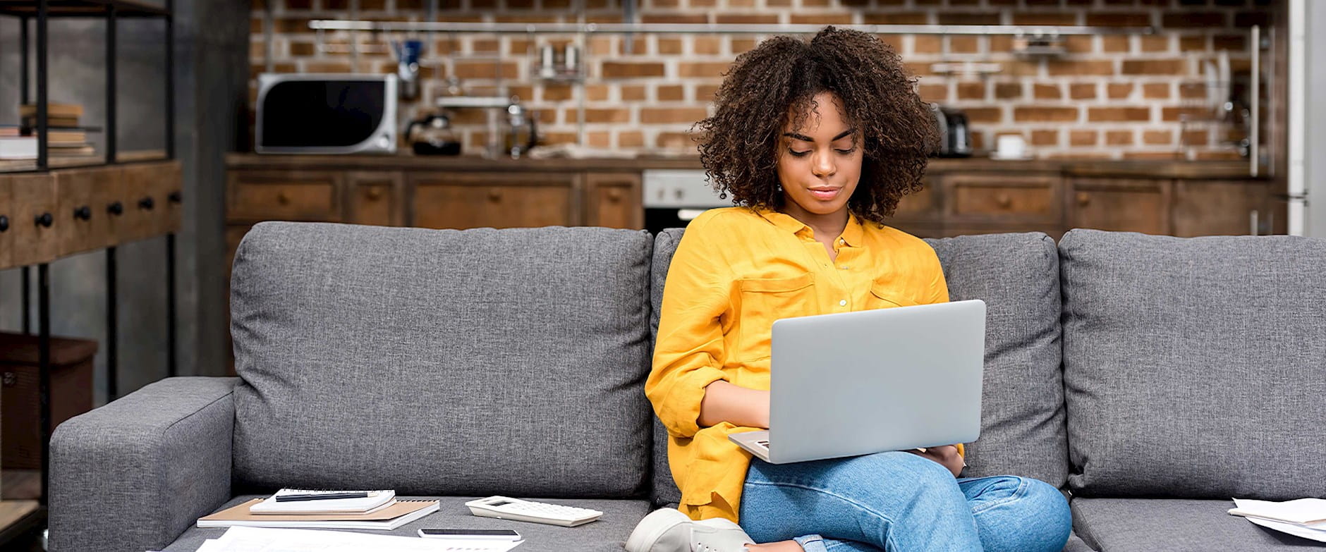 African American woman sitting on a couch using her laptop
