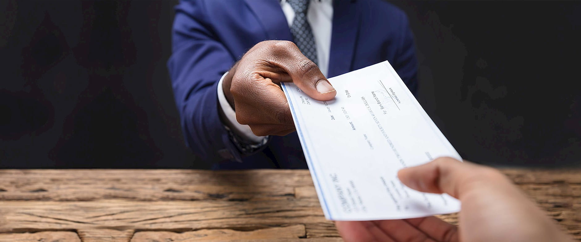 Close up of a person handing a check to another person