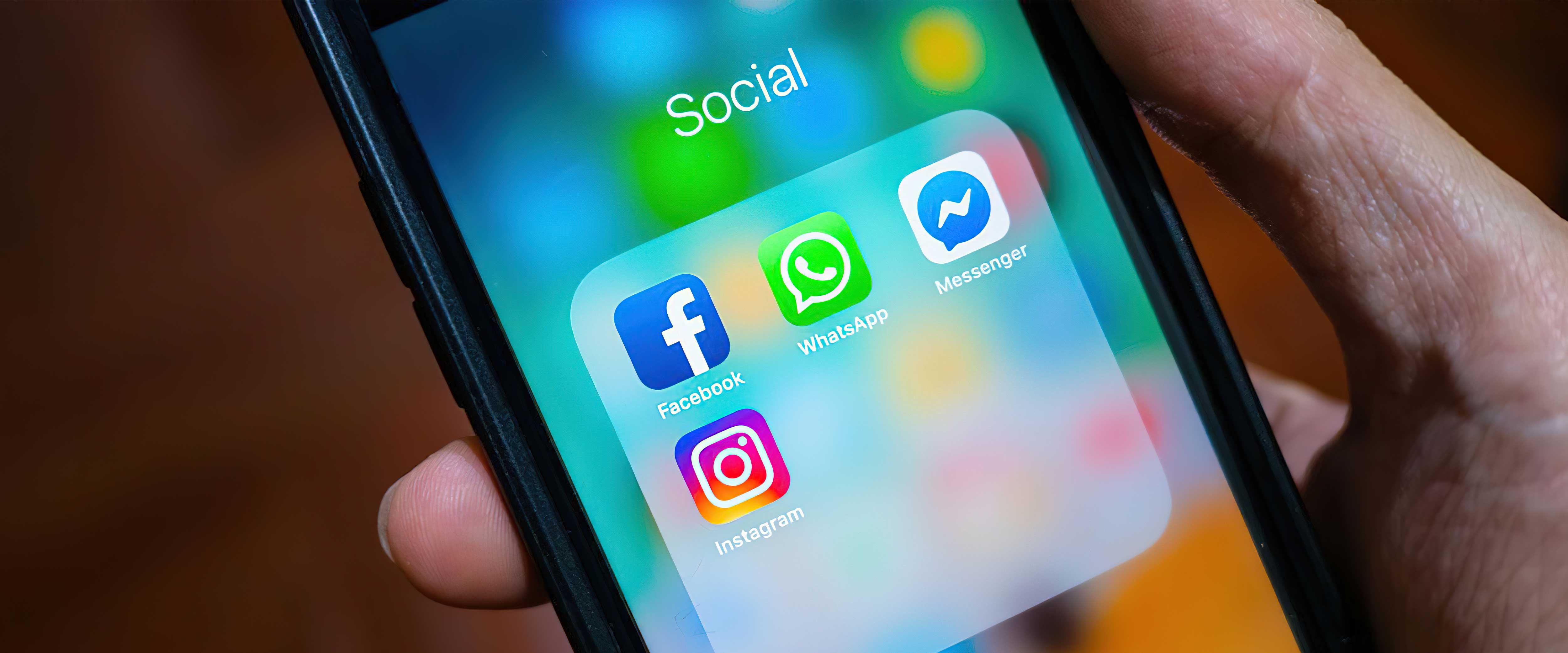 Hand holding a smartphone with social media apps on the screen