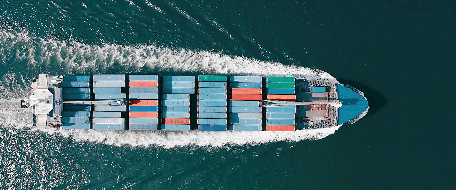 Container ship moving through the ocean as seen from above