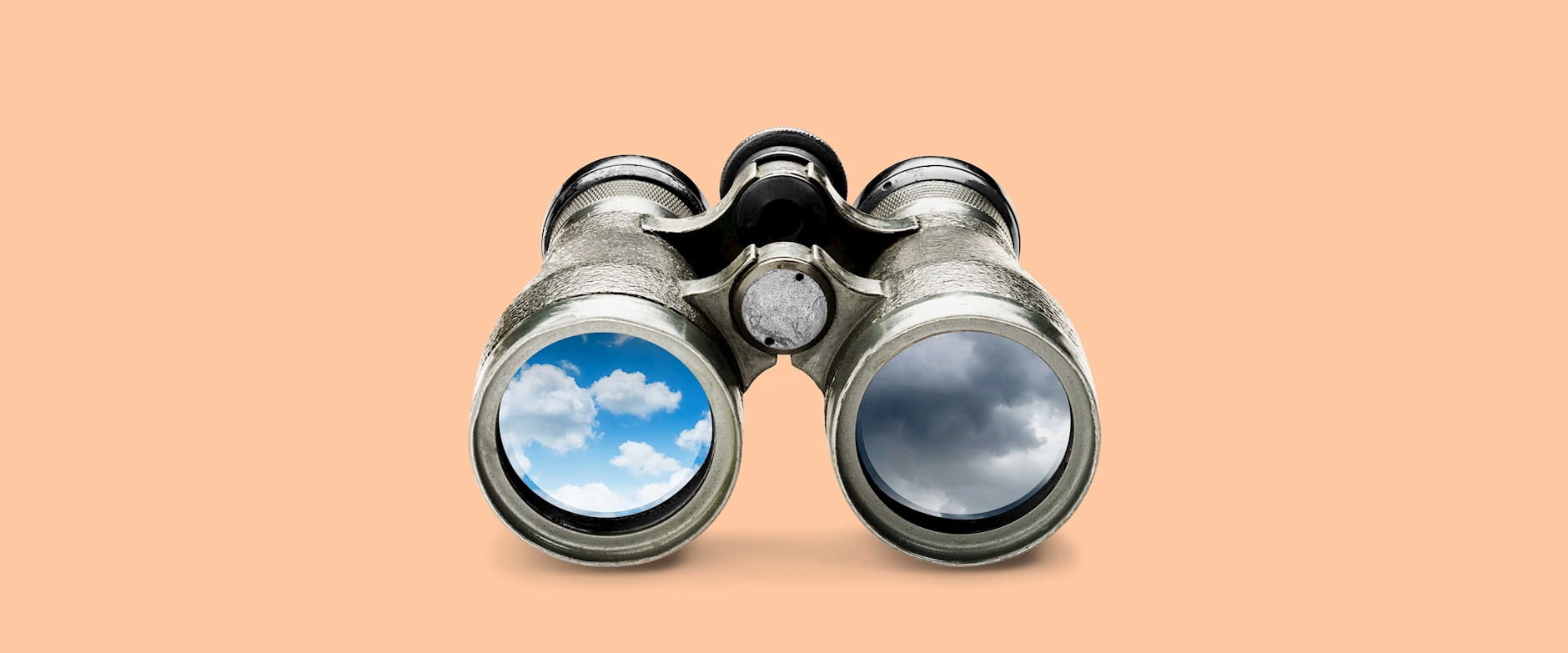 Binoculars with a blue sky reflected in one lens and a stormy sky in the other