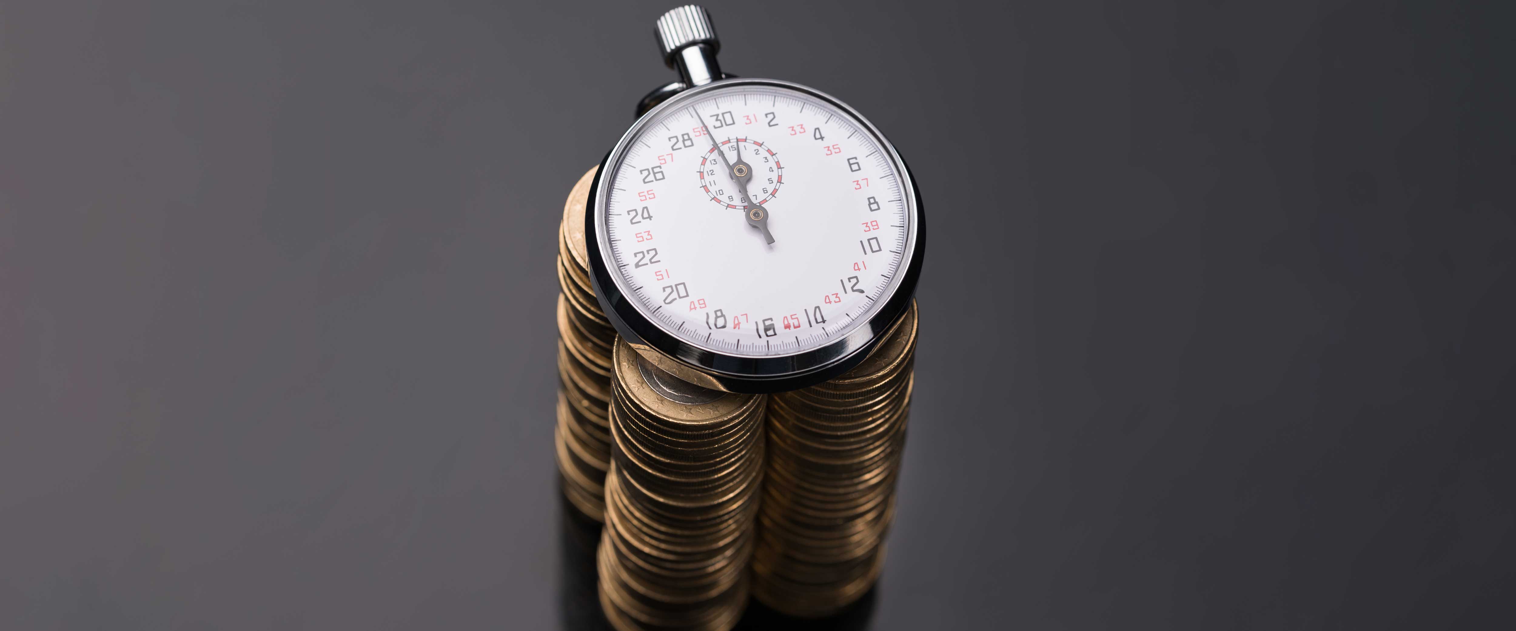 A stopwatch lies on top of a stack of euro coins
