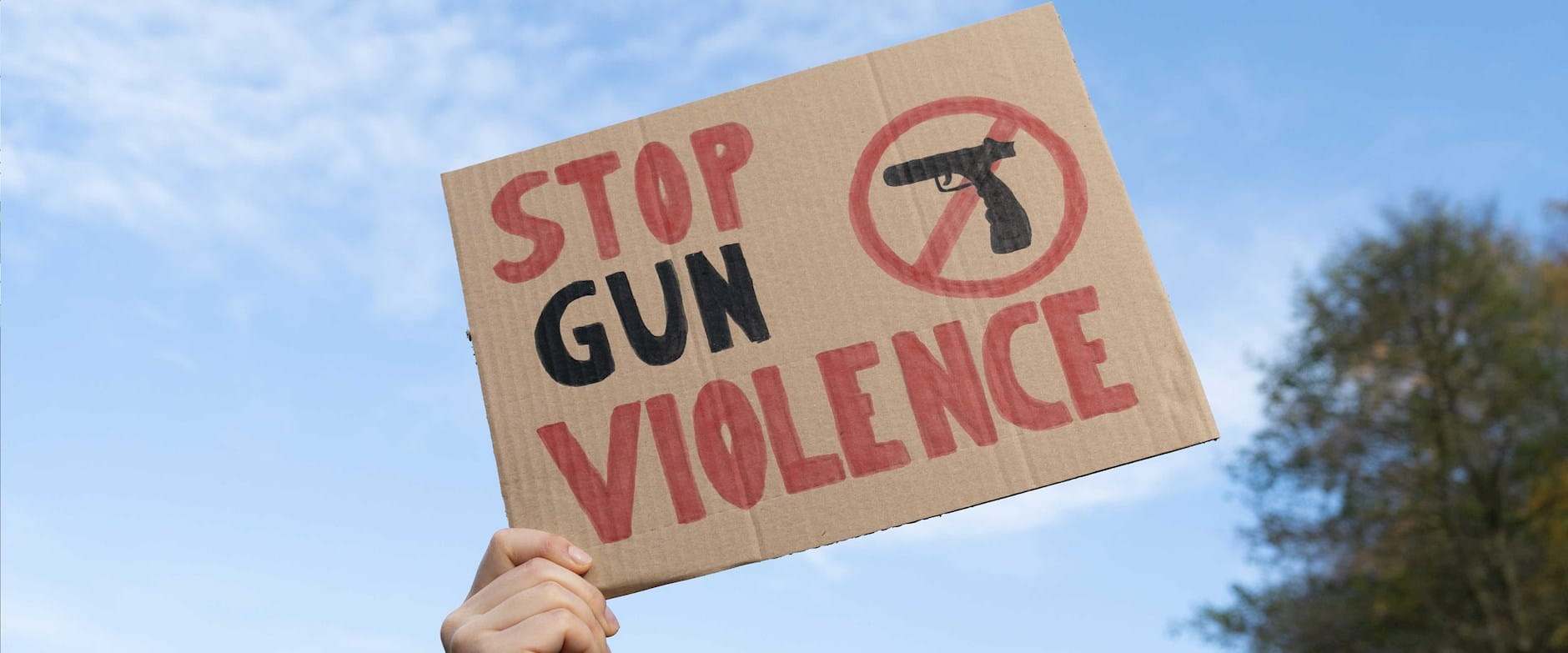 Hand holding a sign that says, "Stop gun violence"