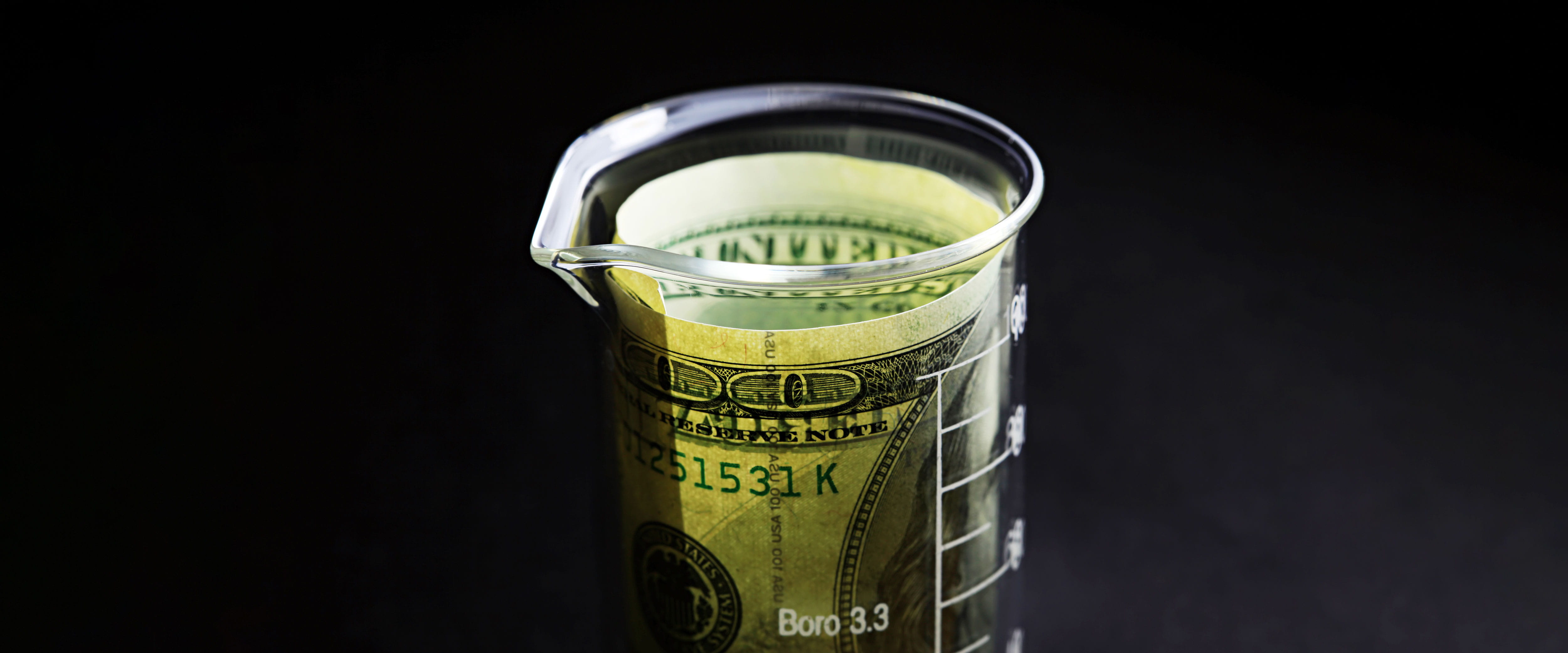 Laboratory beaker with dollar bill inside it