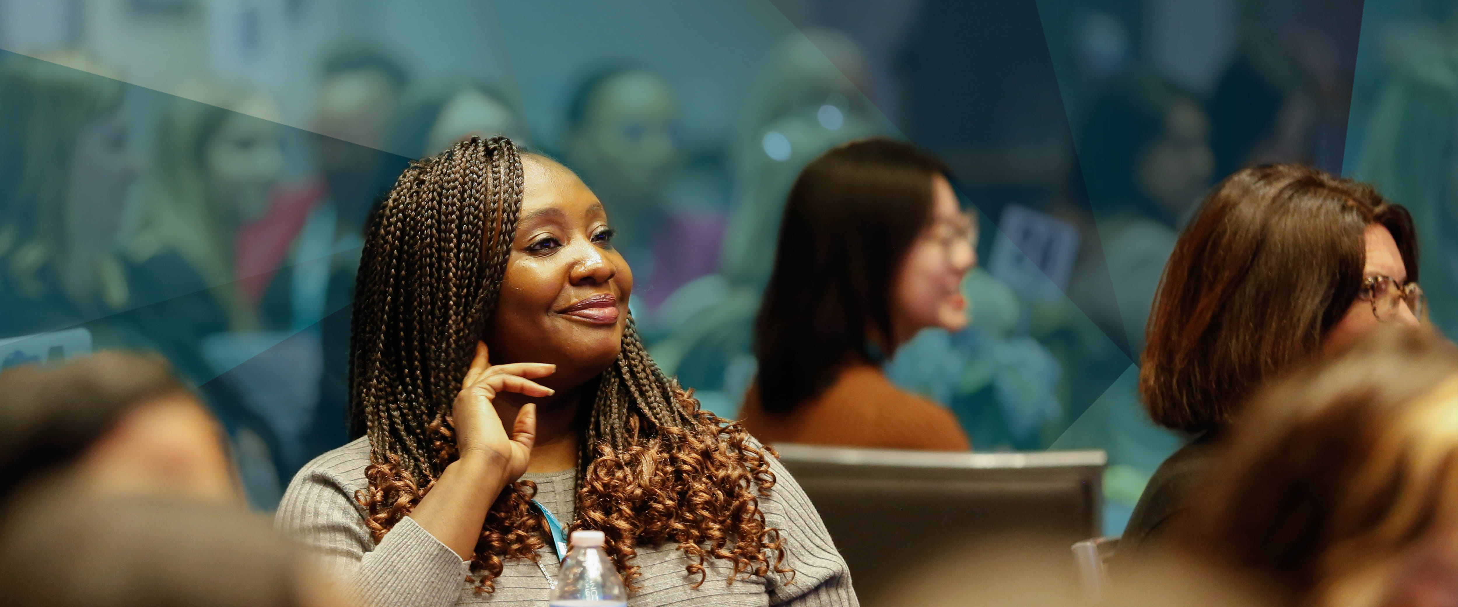 A woman in the audience of the Booth Women Connect event smiling and interested