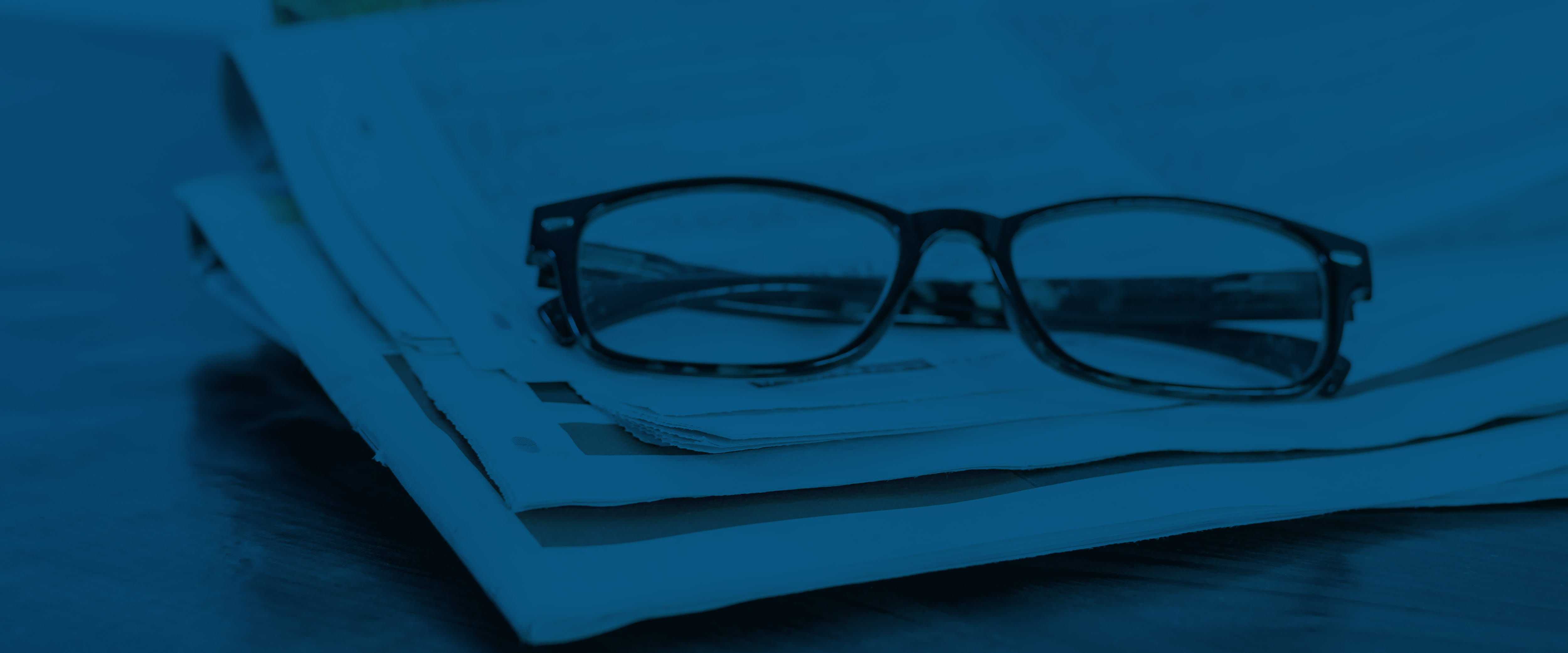 A pair of glasses resting on a stack of newspapers
