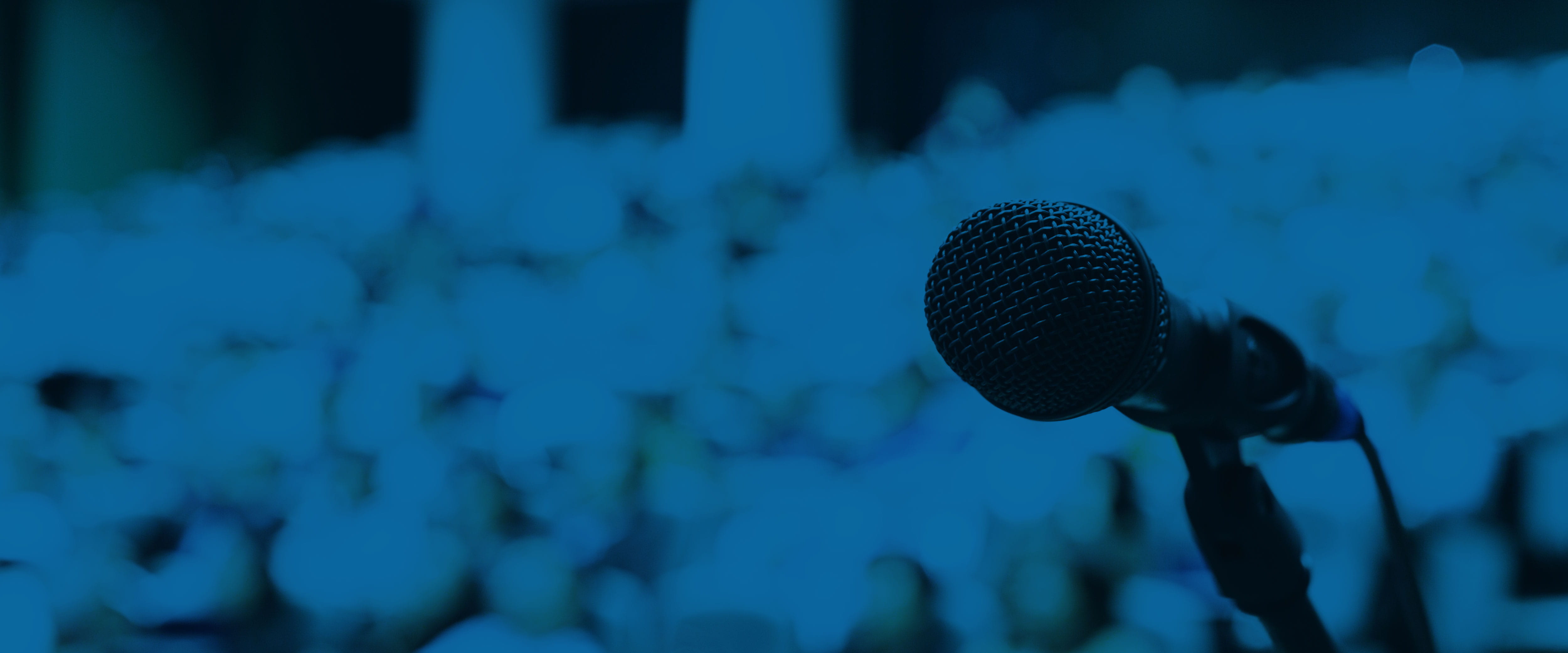 A microphone on the right side of the screen overlooks a blurry, packed audience