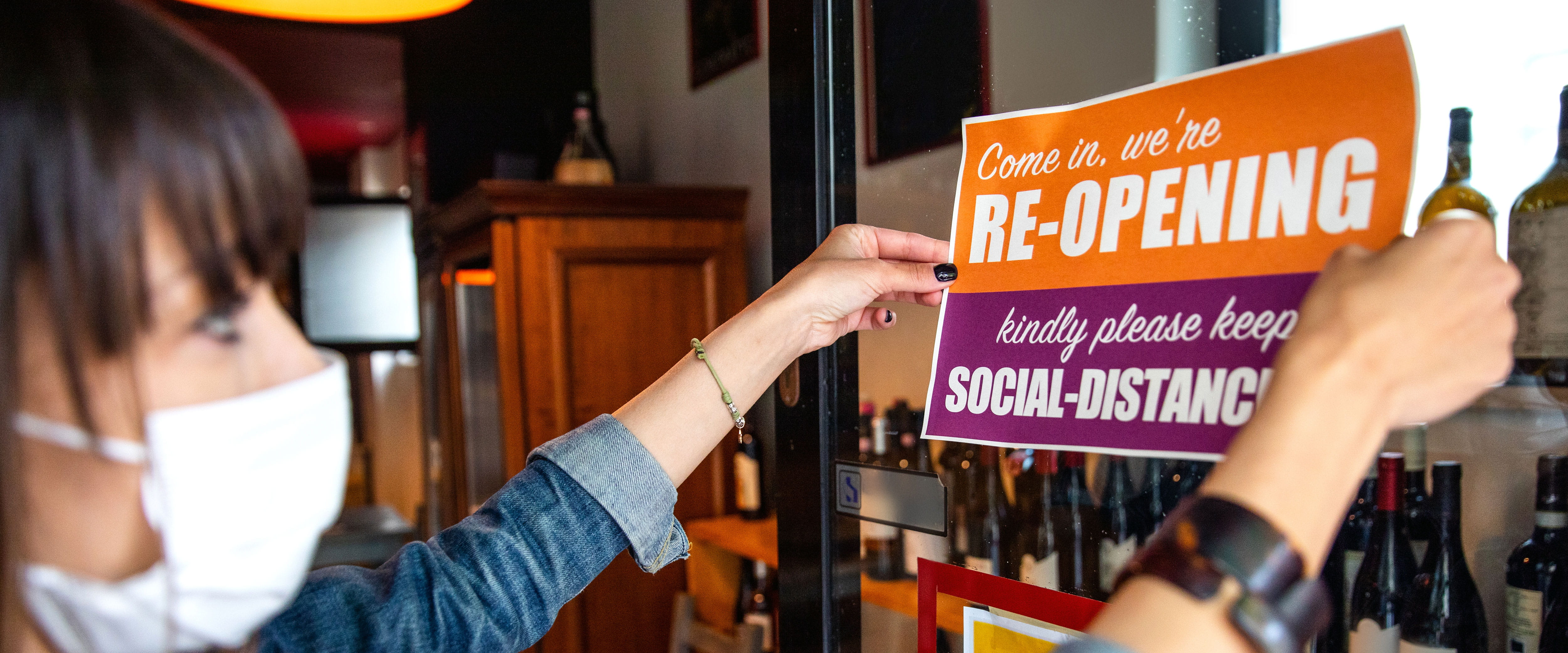 Business with a person putting up a sign that they are open for business