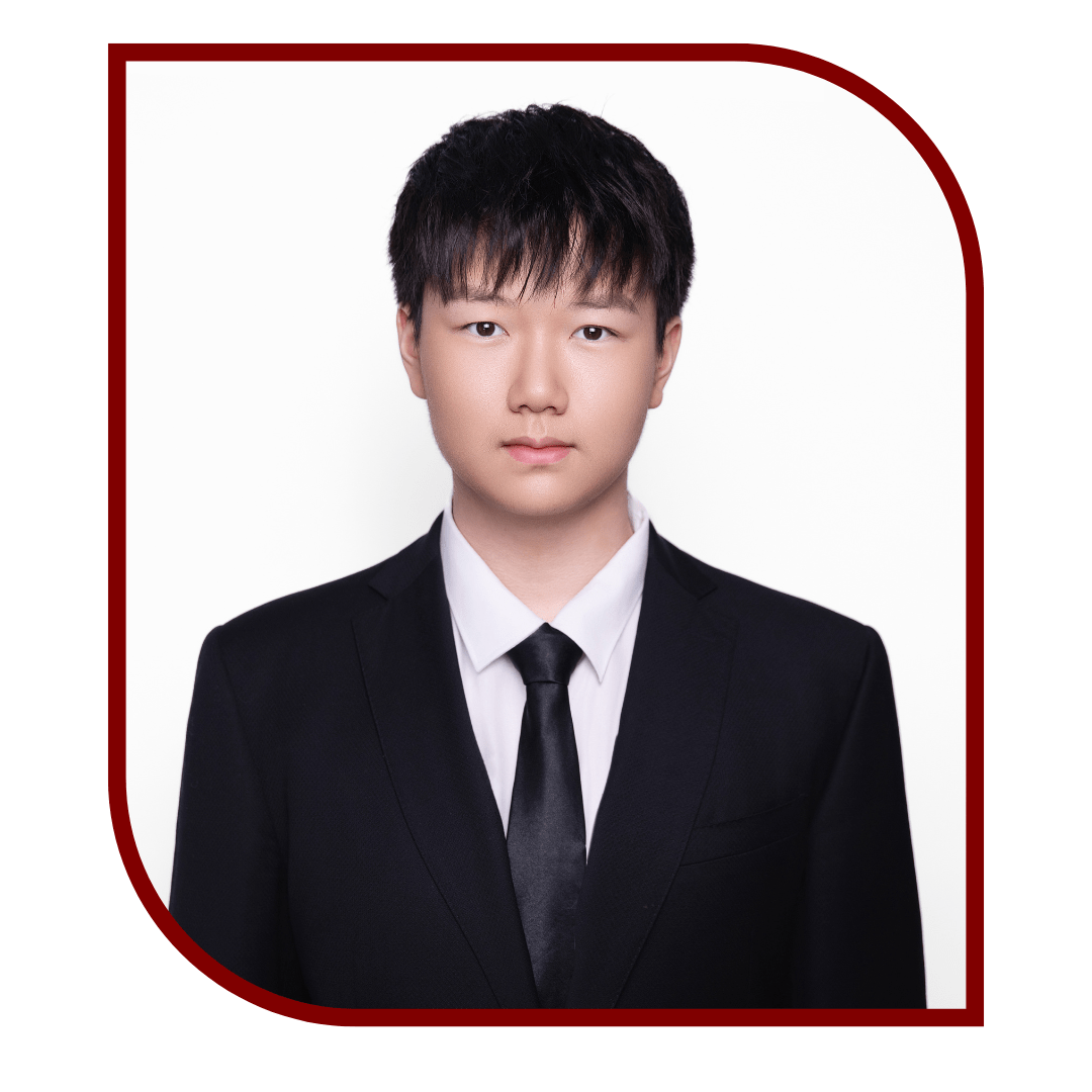 Picture of dark-haired young man wearing a tux and standing in front of a white background. The picture is bordered by a maroon frame. 