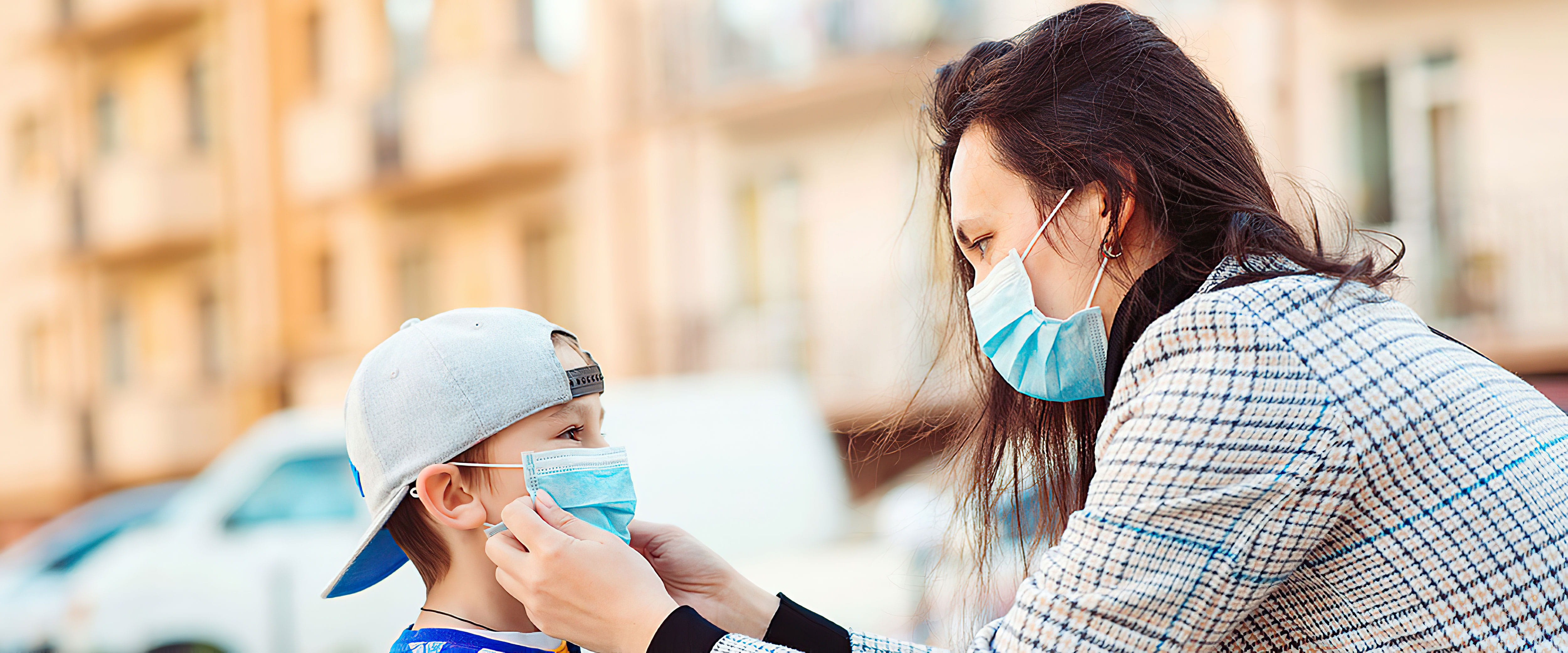 Woman wearing a mask putting one on her son
